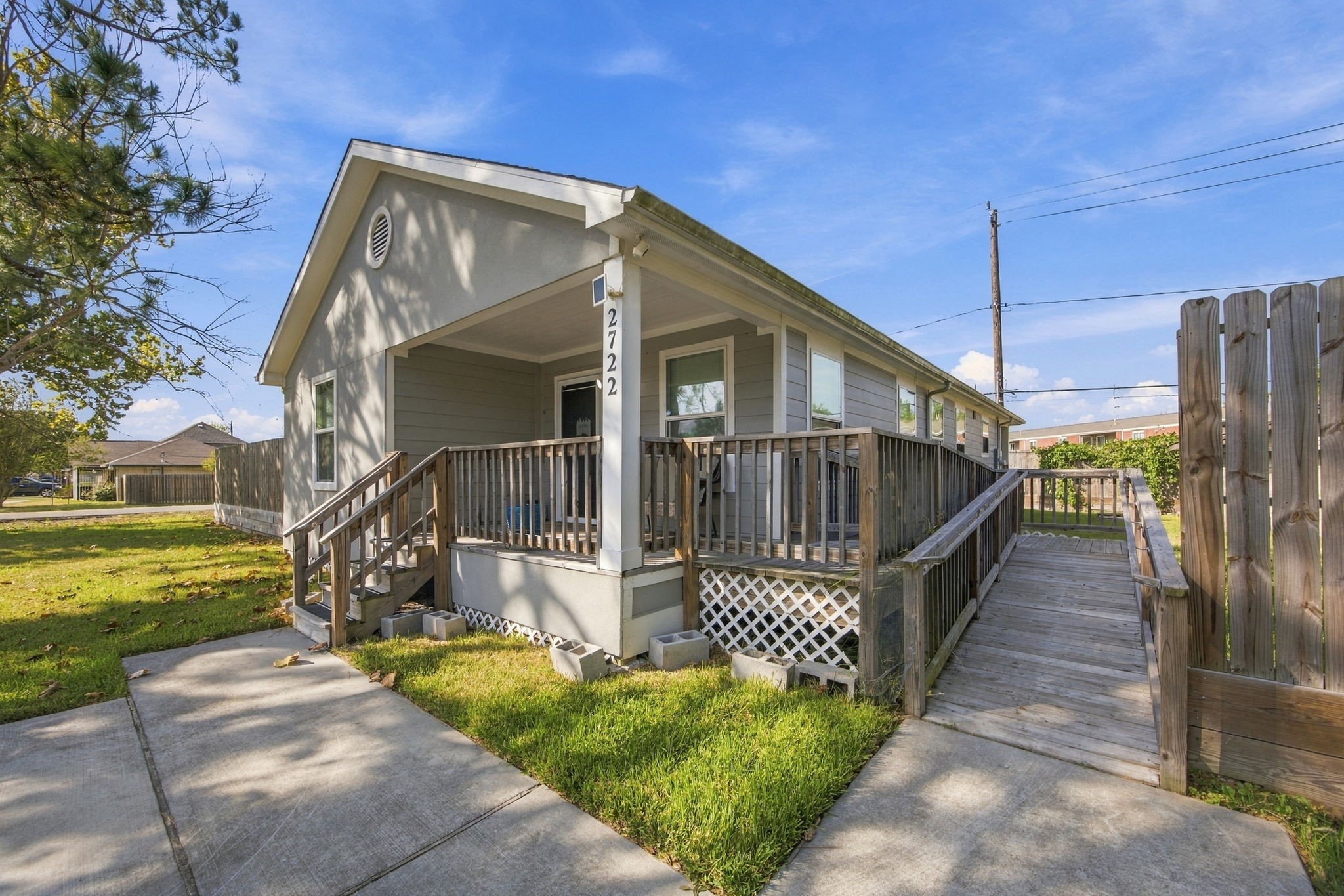 Front and side exterior view featuring the covered porch, wooden ramp, and fenced outdoor space. Front and side exterior view featuring the covered porch, wooden ramp, and fenced outdoor space.