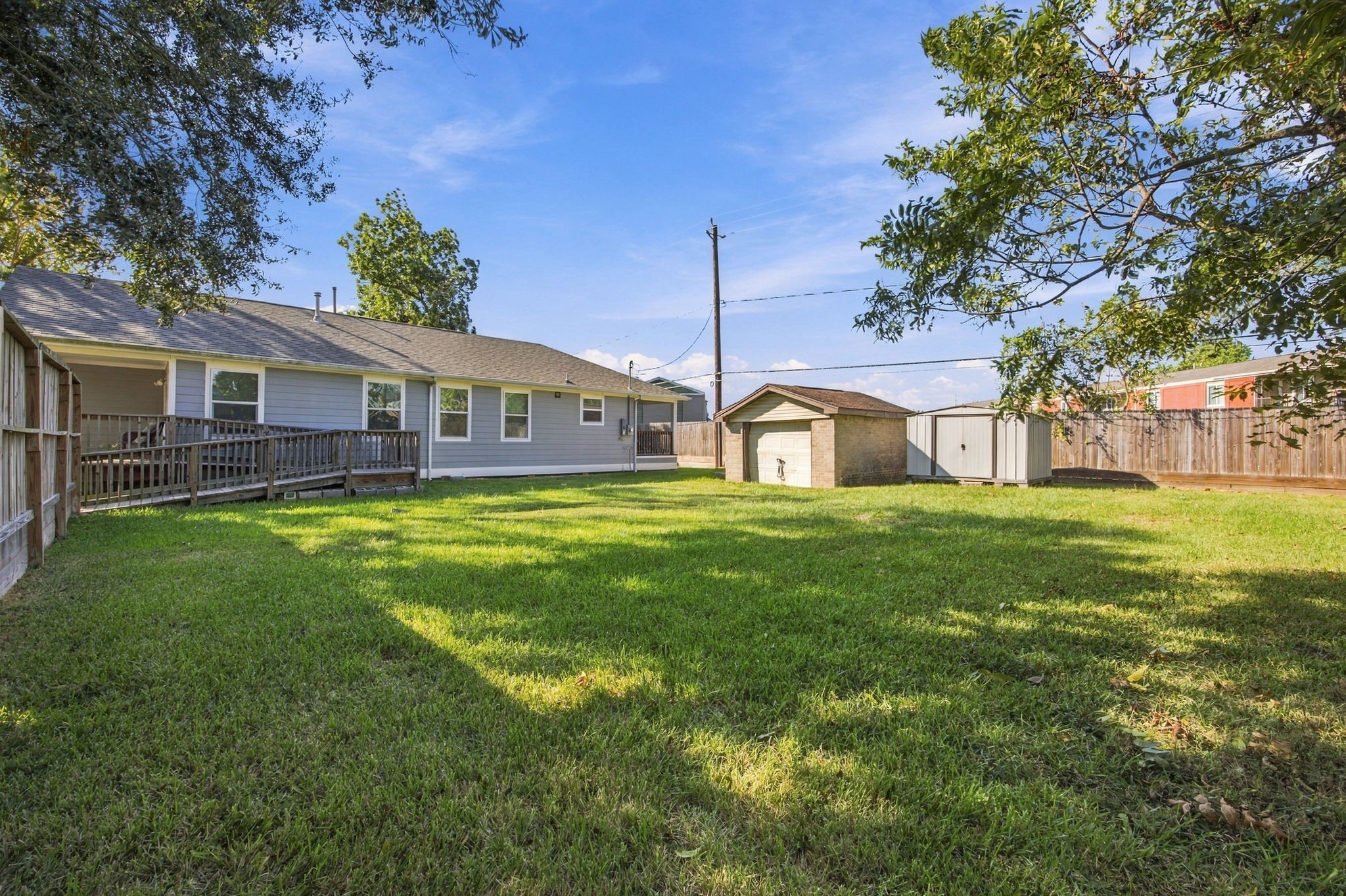 Rear exterior view highlighting the home, elevated deck, and spacious fenced backyard.