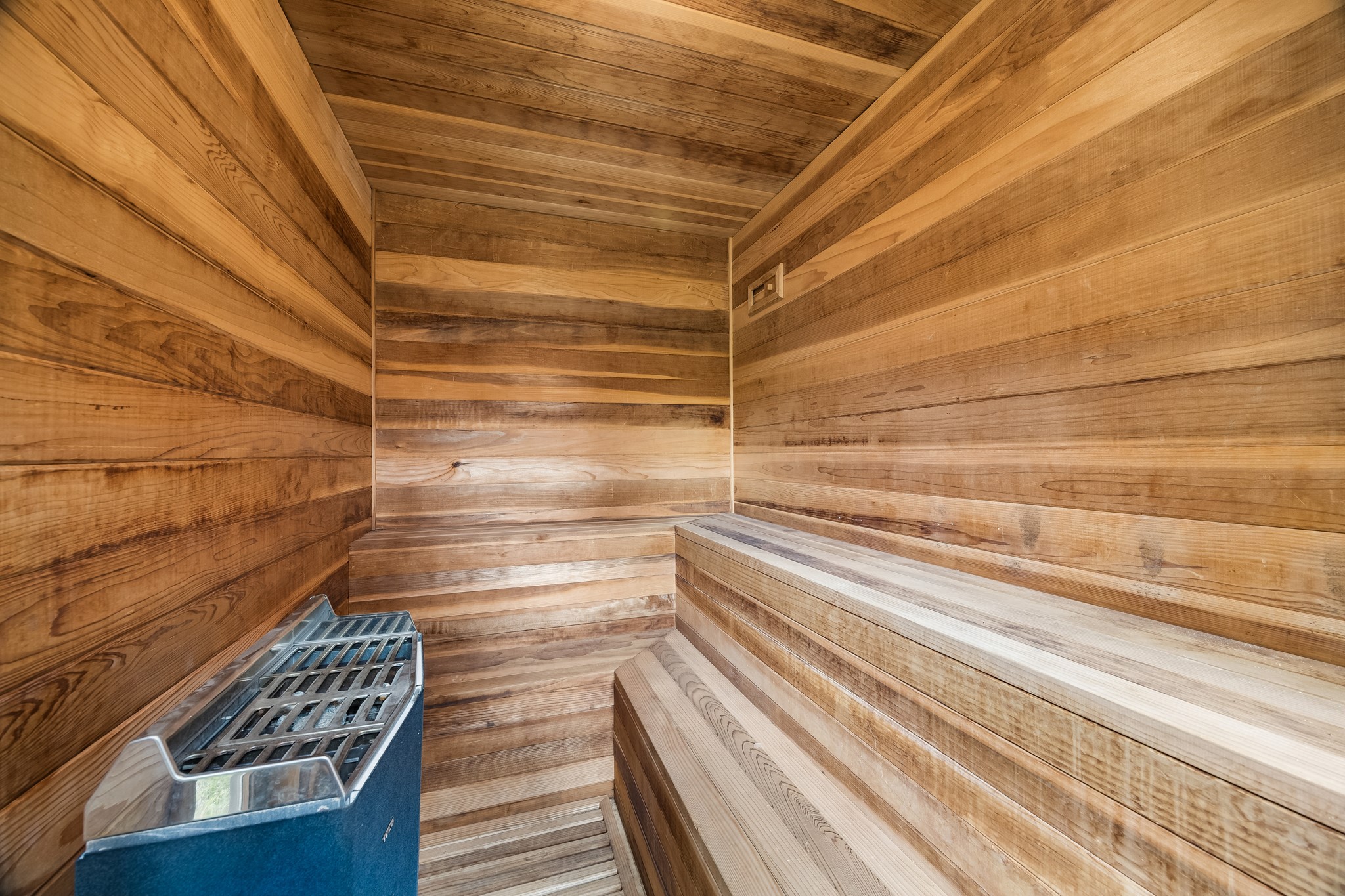 Experience ultimate relaxation in this beautifully crafted wooden sauna, featuring sleek benches and a modern heating unit for a luxurious spa experience at home.