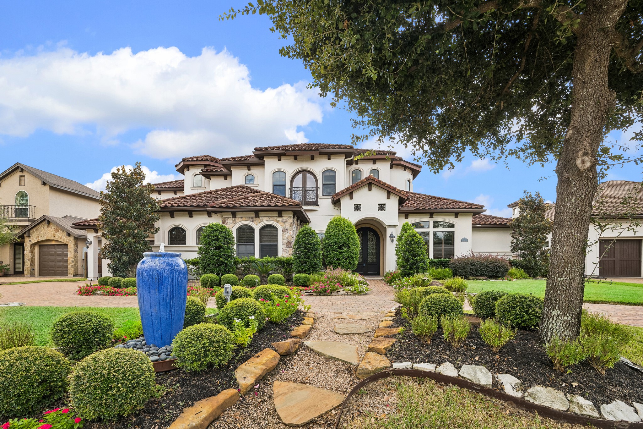 Stunning Mediterranean-style home with a classic tile roof, beautifully manicured landscaping, and a spacious driveway leading to a three-car garage. Stunning Mediterranean-style home with a classic tile roof, beautifully manicured landscaping, and a spacious driveway leading to a three-car garage.