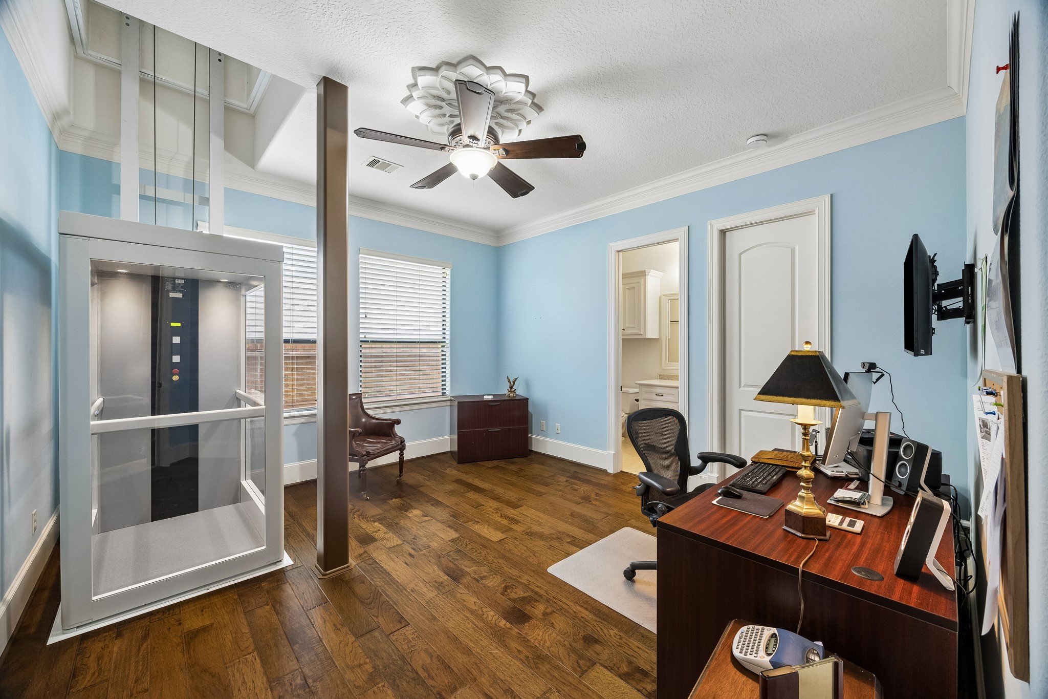 Bright and spacious first floor bedroom with en-suite bathroom features elegant wooden flooring, featuring a modern elevator for easy access, abundant natural light from large windows, and convenient built-in storage.