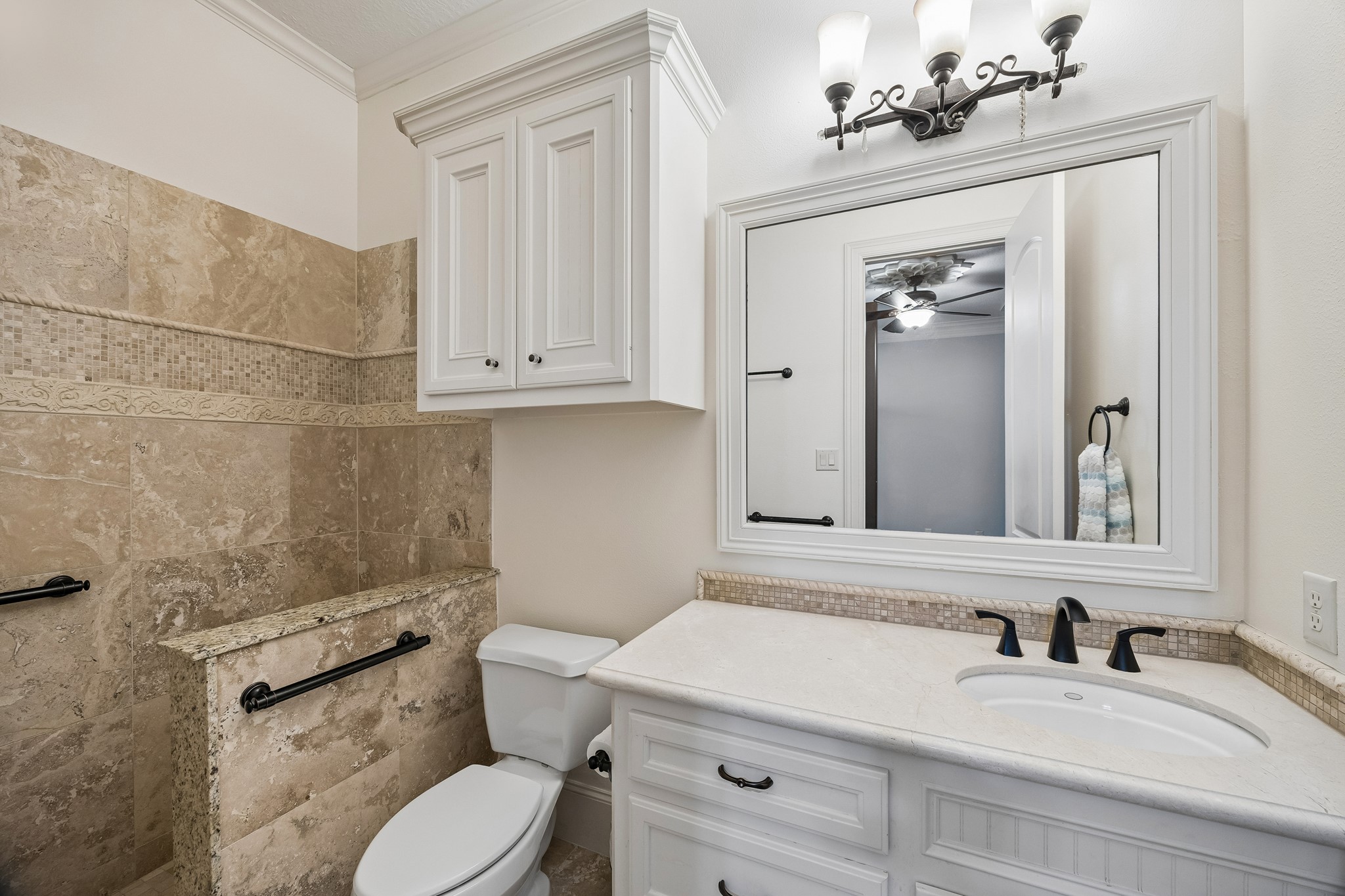 Elegant en-suite bathroom featuring a granite-tiled shower, sleek white cabinetry, and a stylish vanity with a large framed mirror.