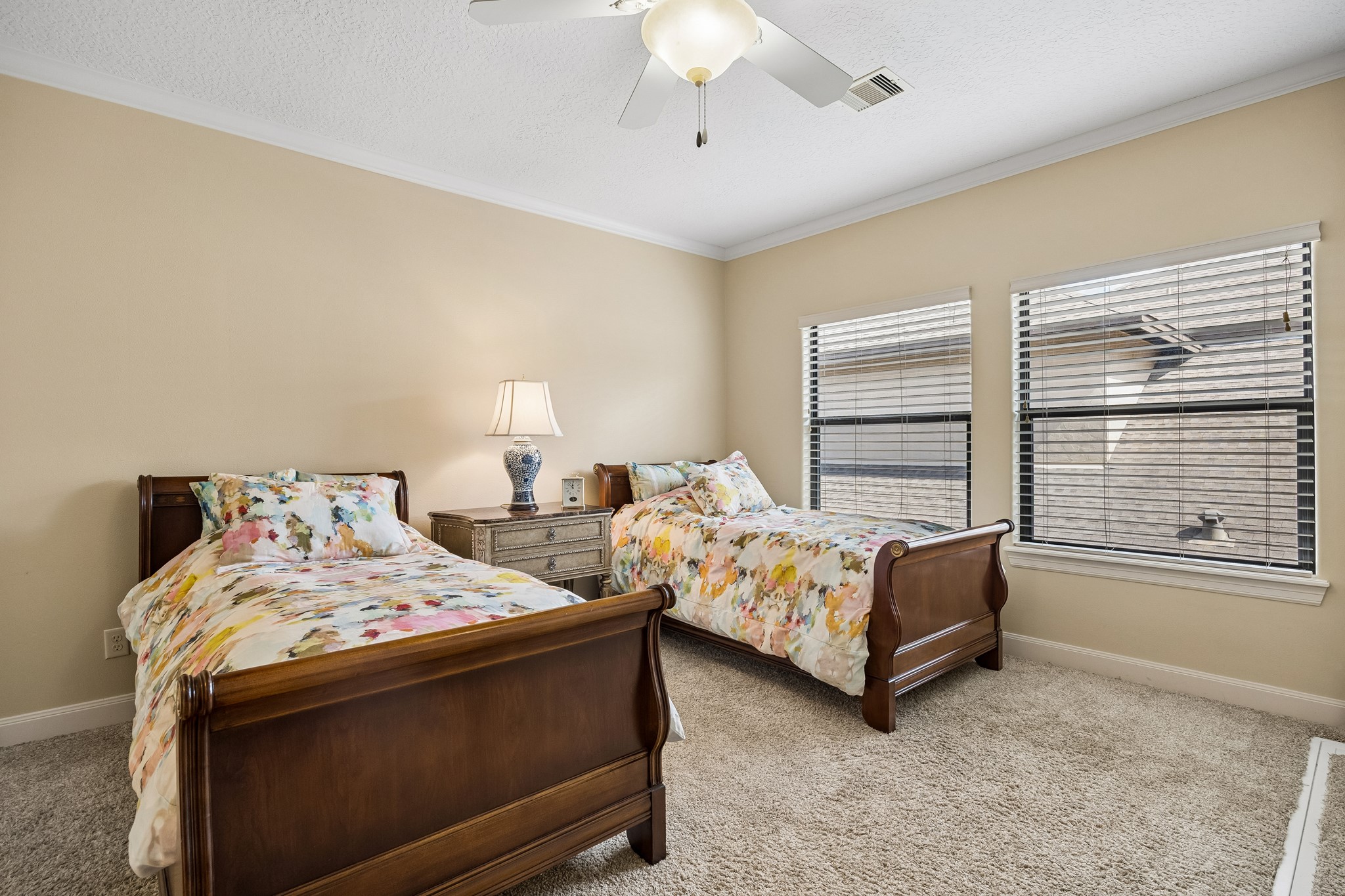 Spacious second floor bedroom with en-suite bathroom, warm neutral walls, and soft carpeting, illuminated by natural light from two large windows.