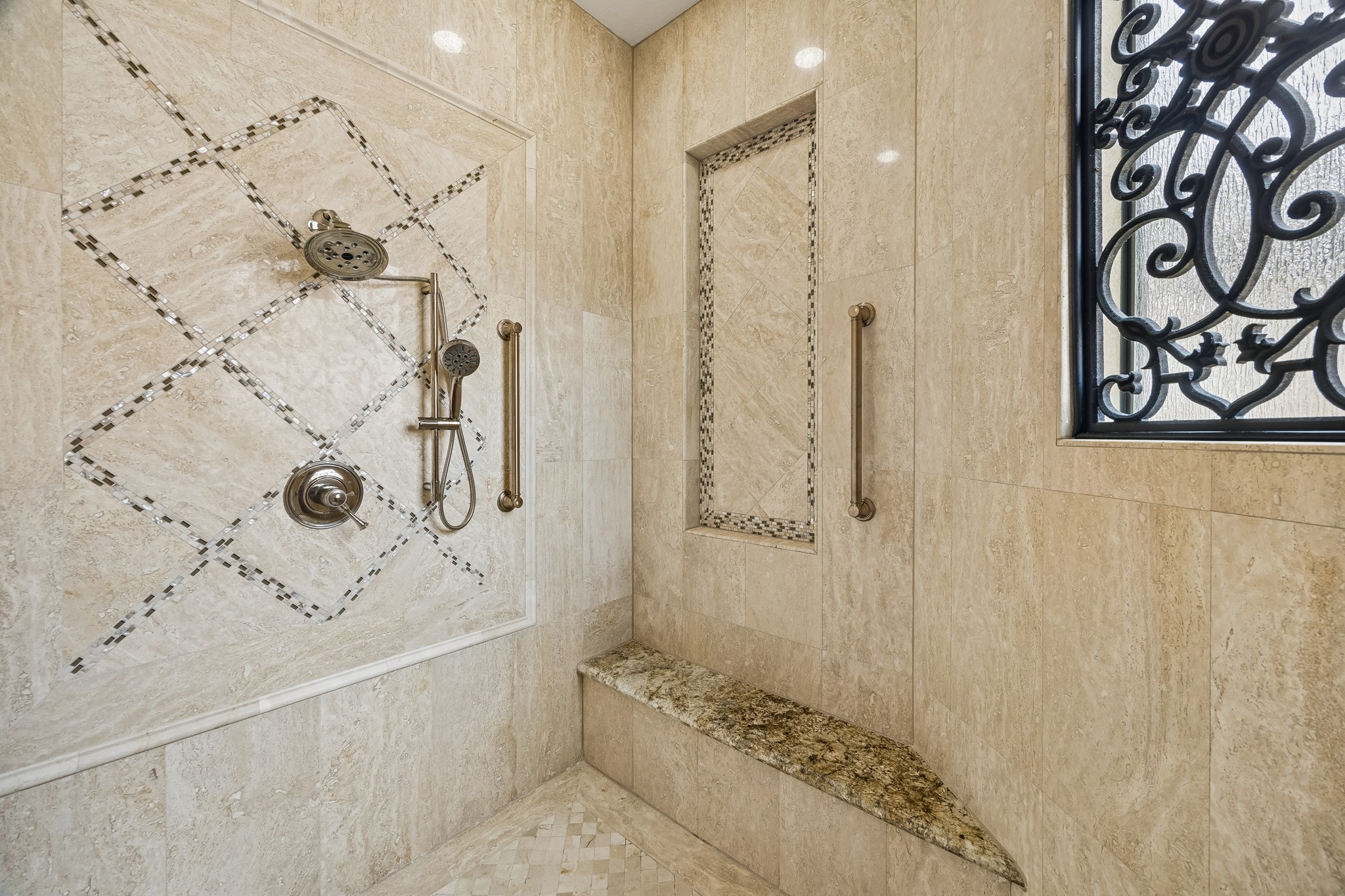 Luxurious shower featuring elegant tile work, a built-in bench, and a stylish wrought iron window for a touch of sophistication.