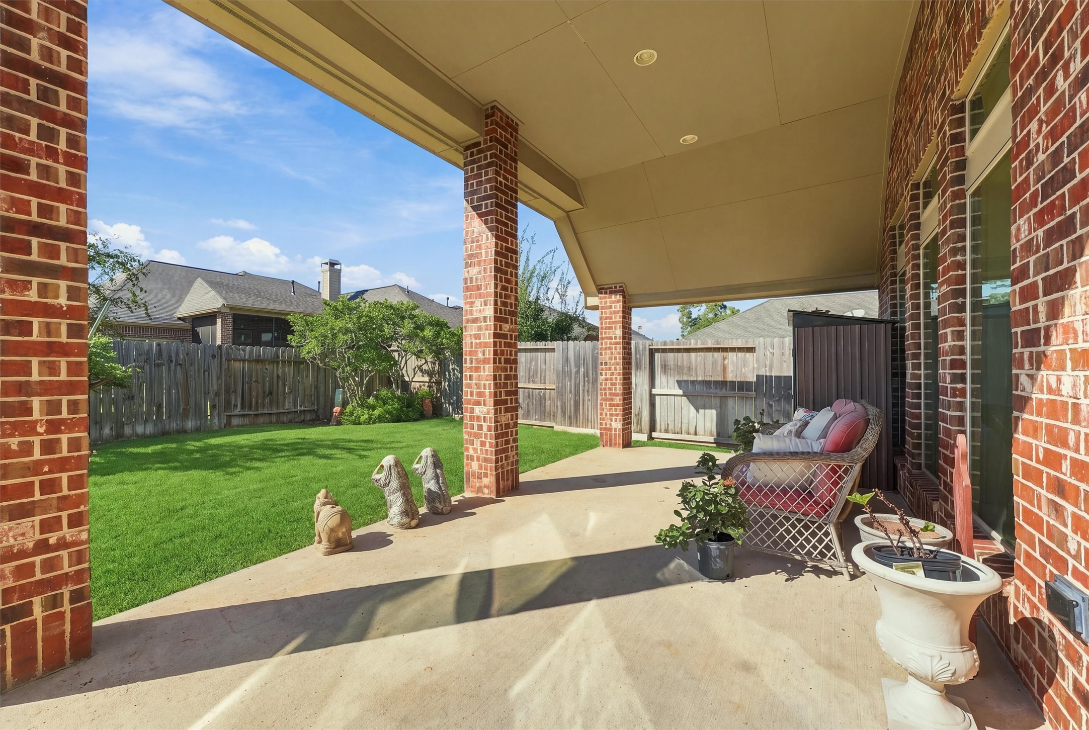 Gorgeous covered patio with high ceiling and brick columns.