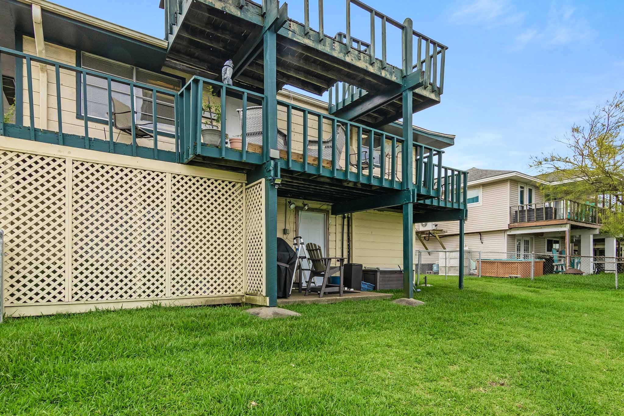 Canal side of home showing small patio on first level and decks on second and third level.