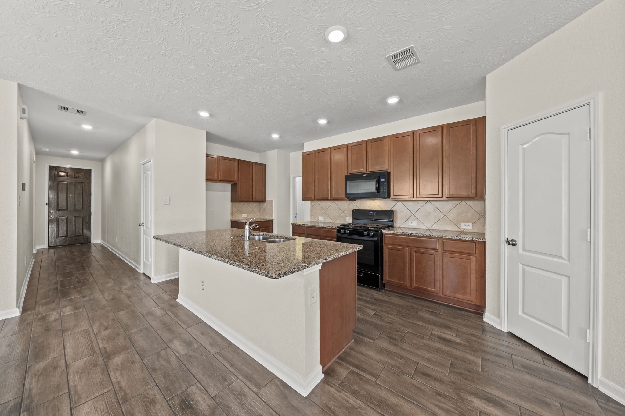 Designed for easy cooking and entertaining, this kitchen boasts rich cabinetry, granite countertops, and a central island.