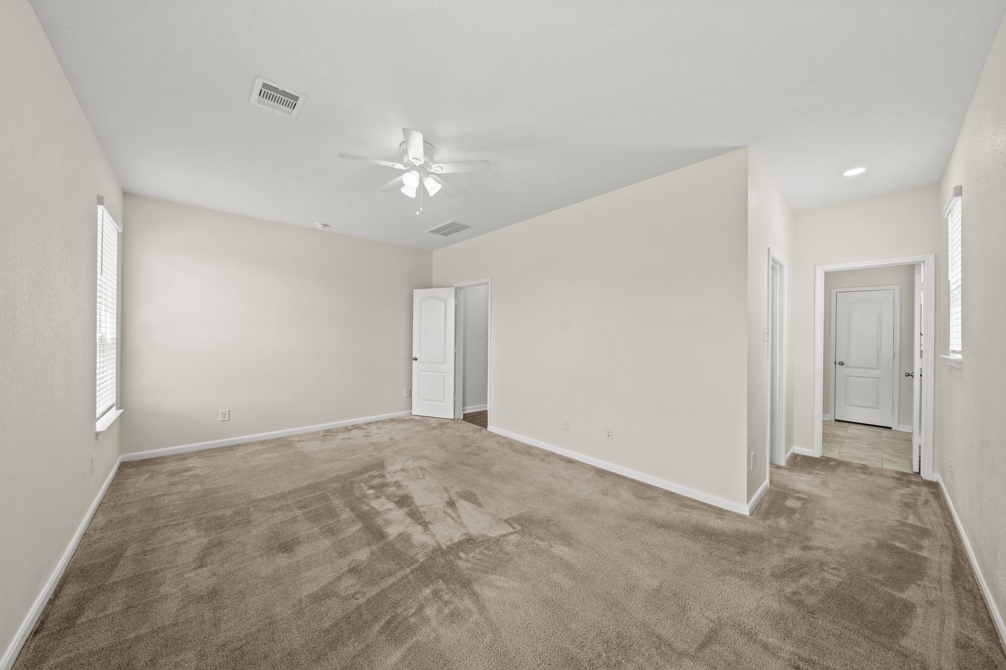 Generously primary bedroom featuring plush carpeting, a ceiling fan, and neutral tones.