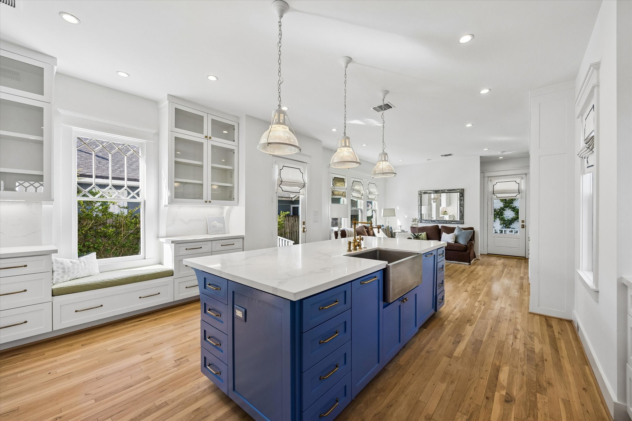 GLEAMING KITCHEN WITH APRON SINK AND BRASS HARDWARE IS OPEN TO THE INFORMAL LIVING ROOM.