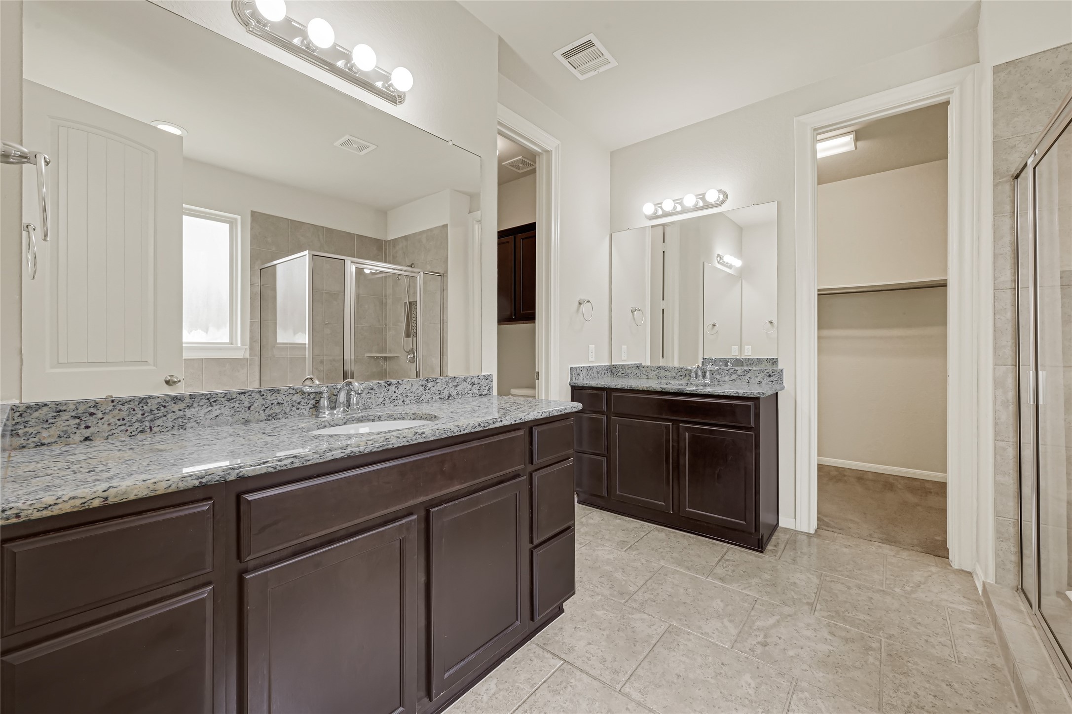 Expansive bathroom vanity with dark cabinetry, dual sinks, large mirrors, and abundant counterspace.