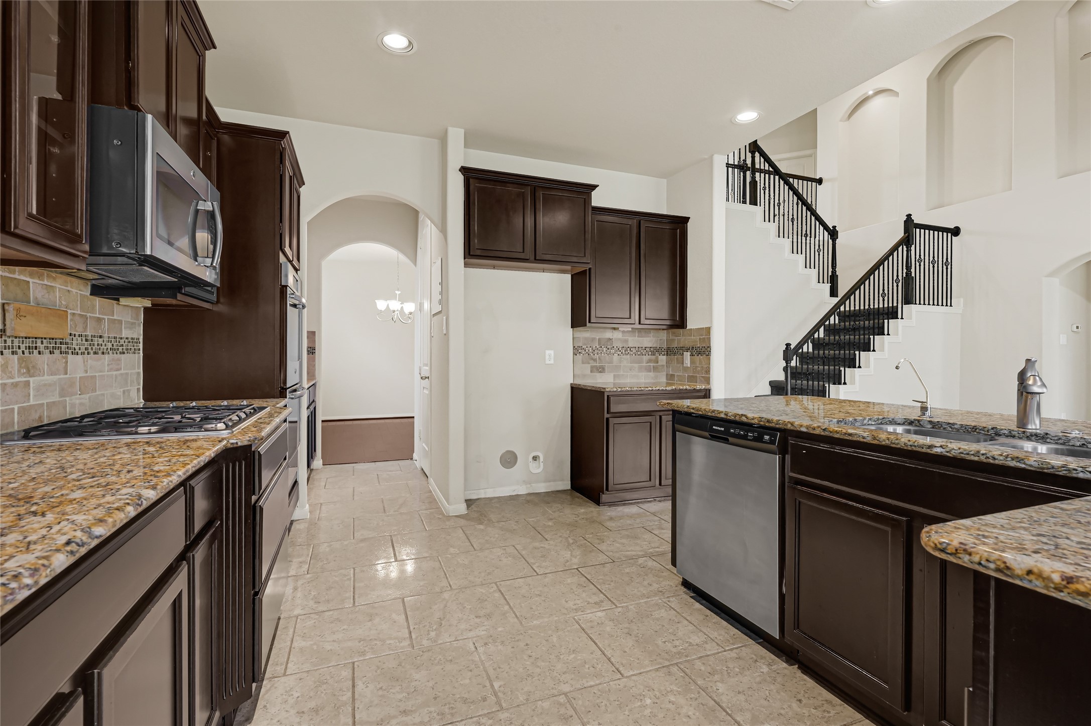 Spacious kitchen with dark cabinetry, granite countertops, stainless steel appliances, and an open layout.