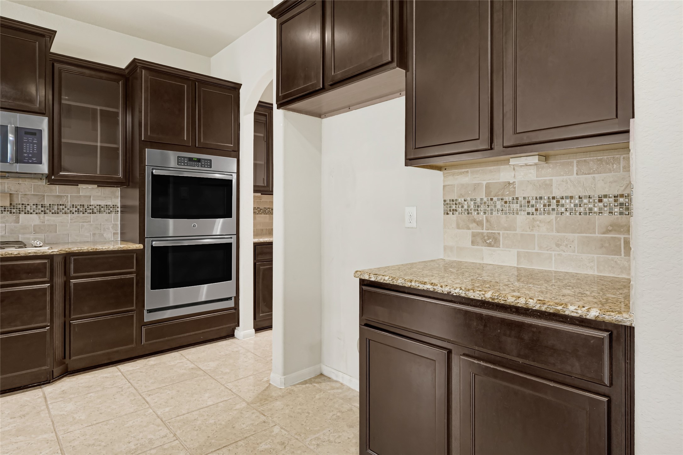 Built-in double ovens, extensive cabinetry, granite counters, and a tiled backsplash