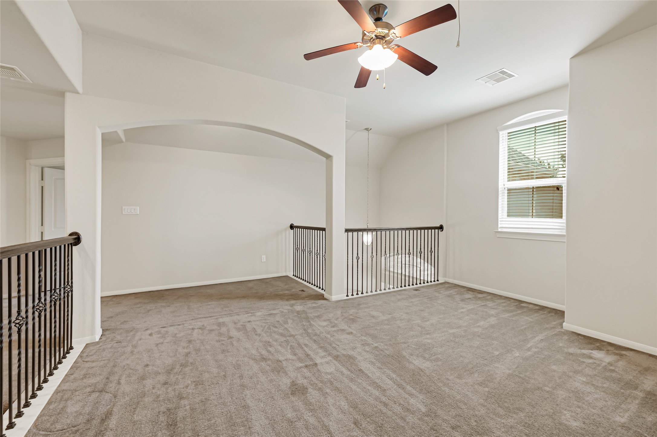 Large flexible living area with a ceiling fan, neutral carpet, and plenty of room for entertainment.