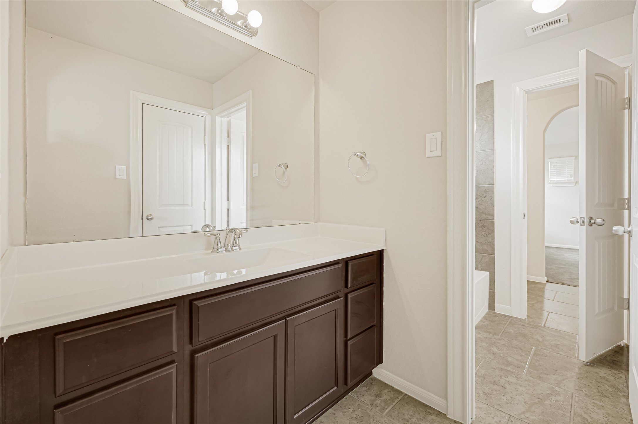 Long vanity with dark cabinetry, ample counter space, and a bright neutral finish.