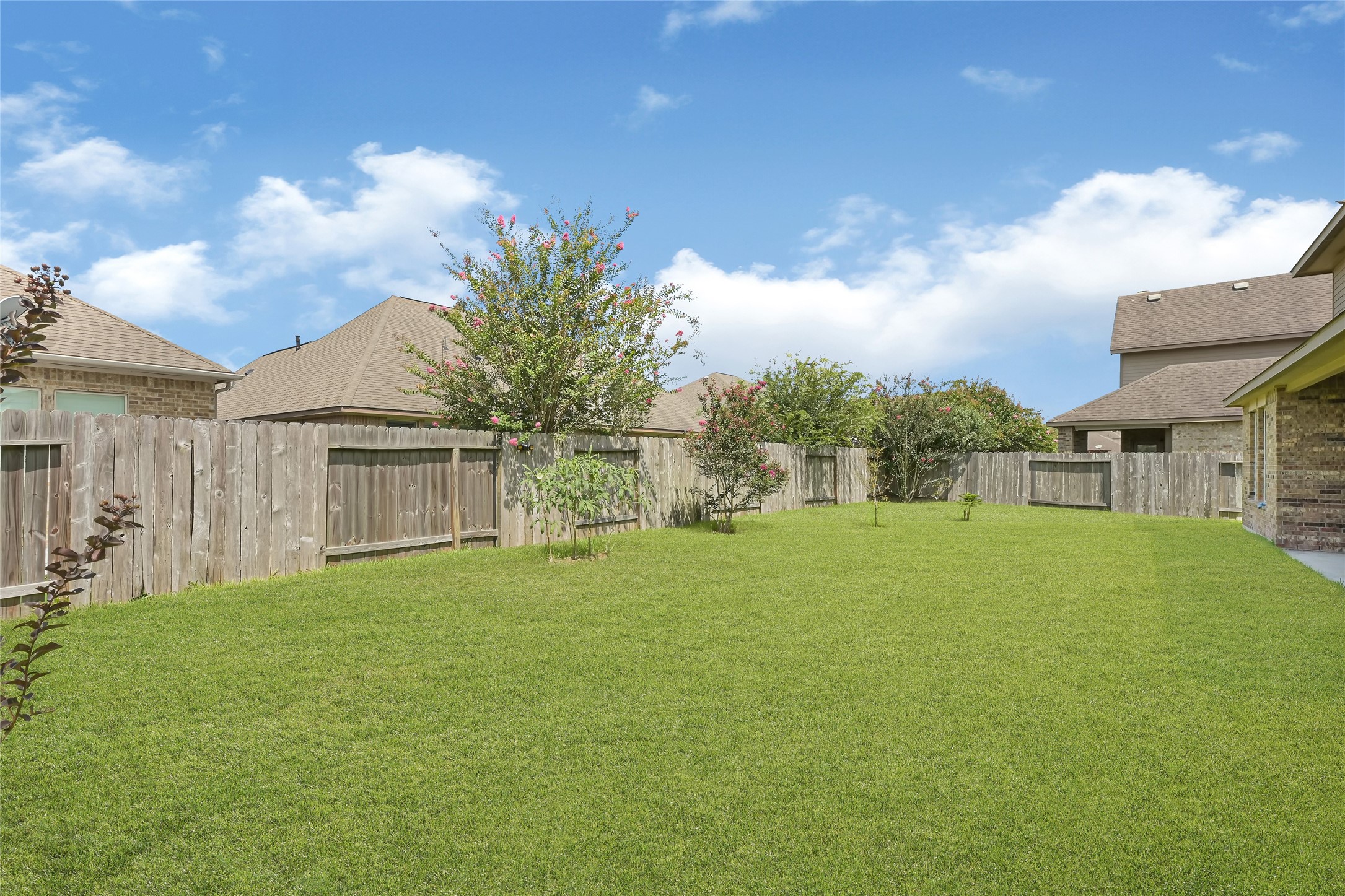 Spacious backyard with a full view of the homes brick exterior and multiple windows