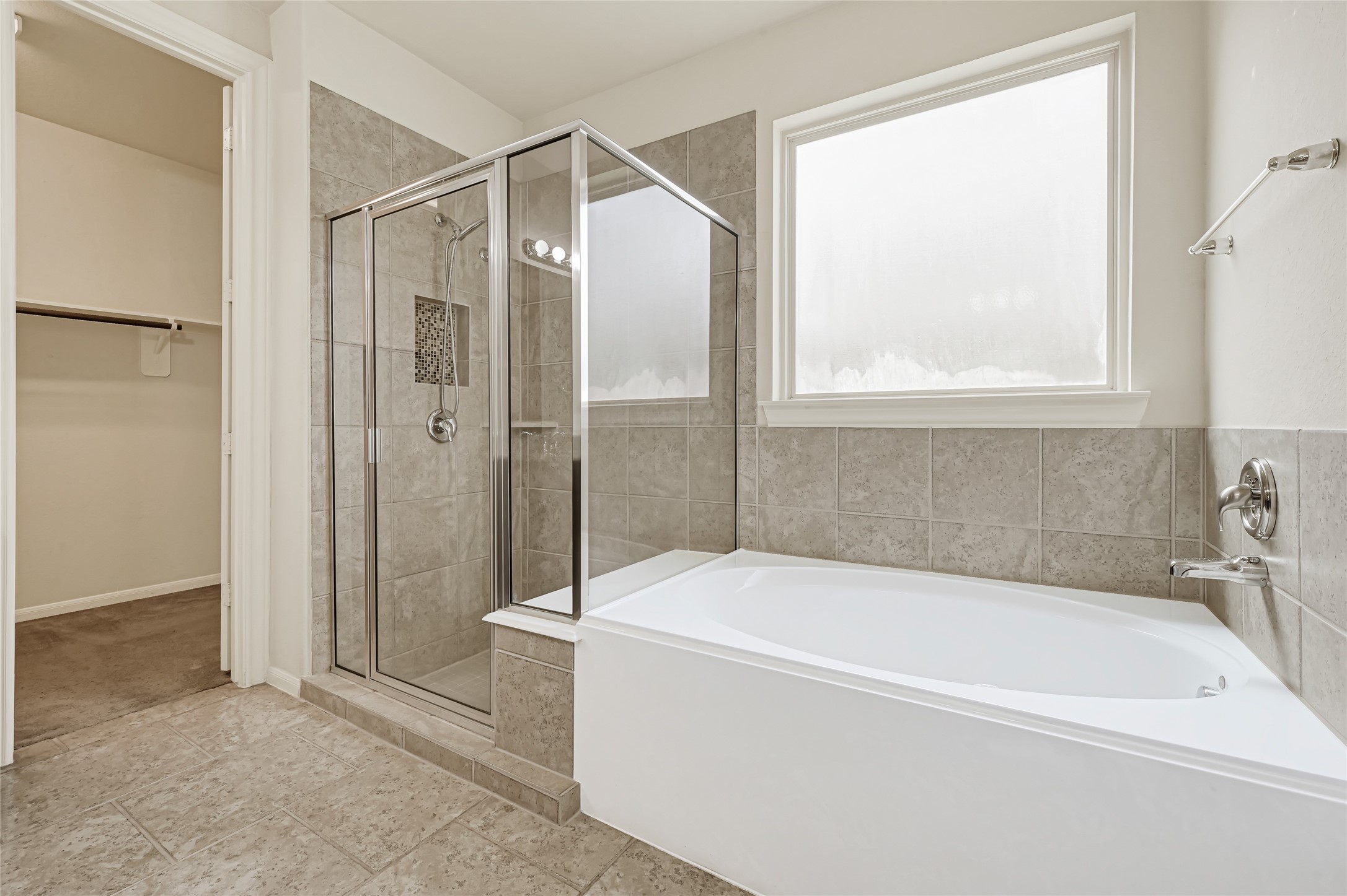 Relaxing primary bath with a soaking tub, separate glass-enclosed shower, and natural light.
