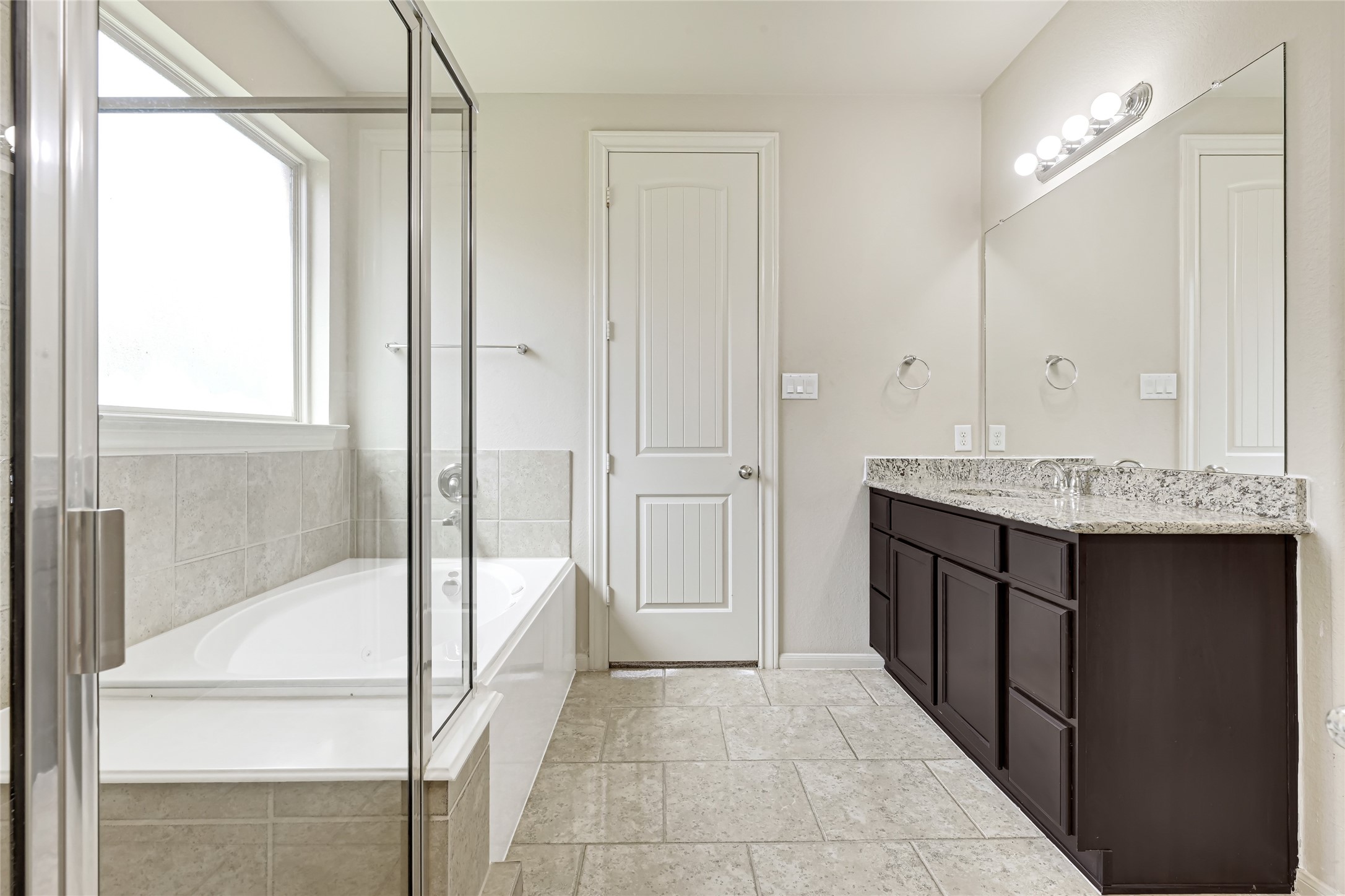 Bright primary bath with a large soaking tub, separate shower, dual vanities, and generous natural light.