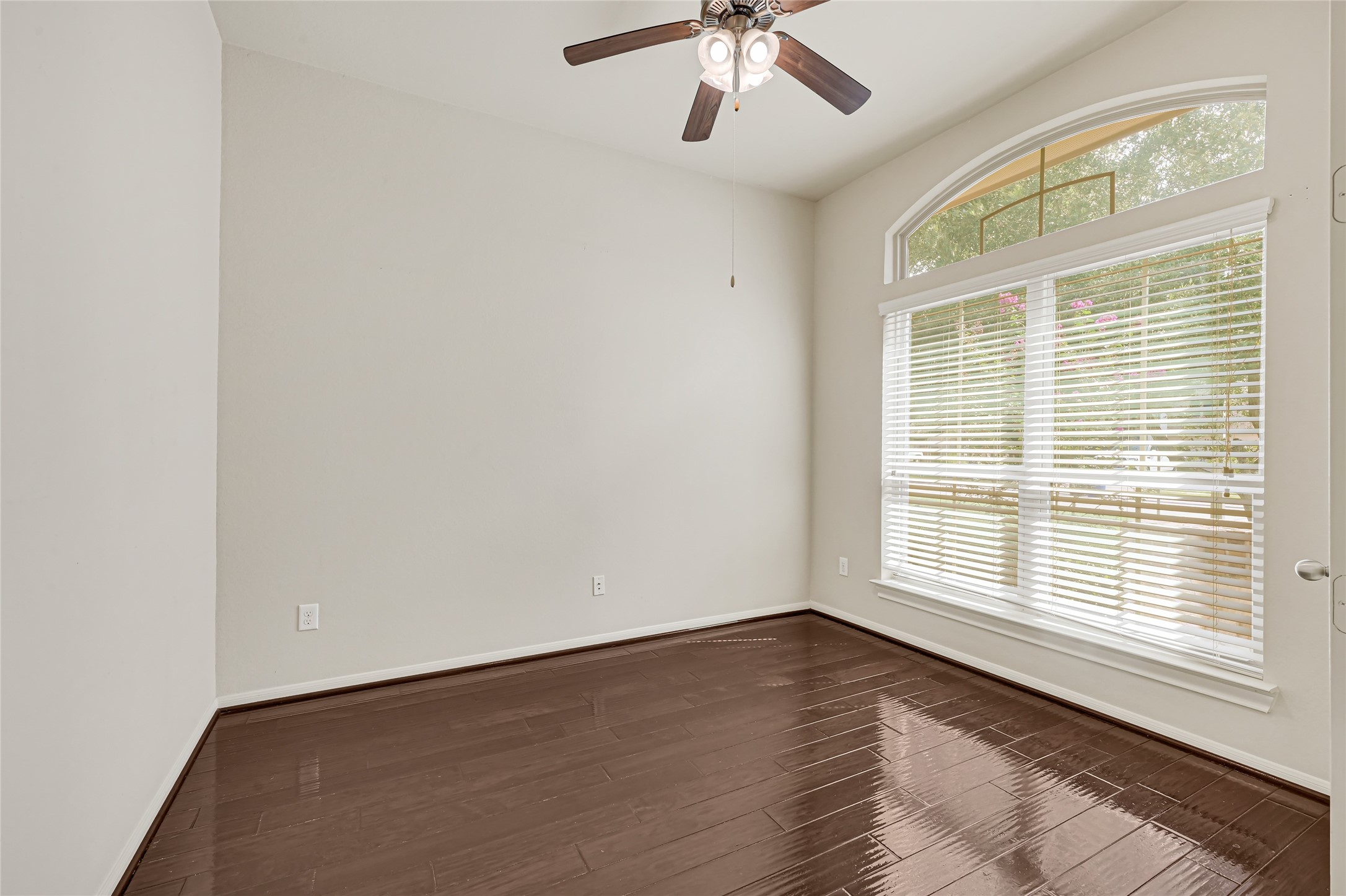 Versatile front room with hardwood flooring, ceiling fan, and a large window overlooking the front yard. Versatile front room with hardwood flooring, ceiling fan, and a large window overlooking the front yard.