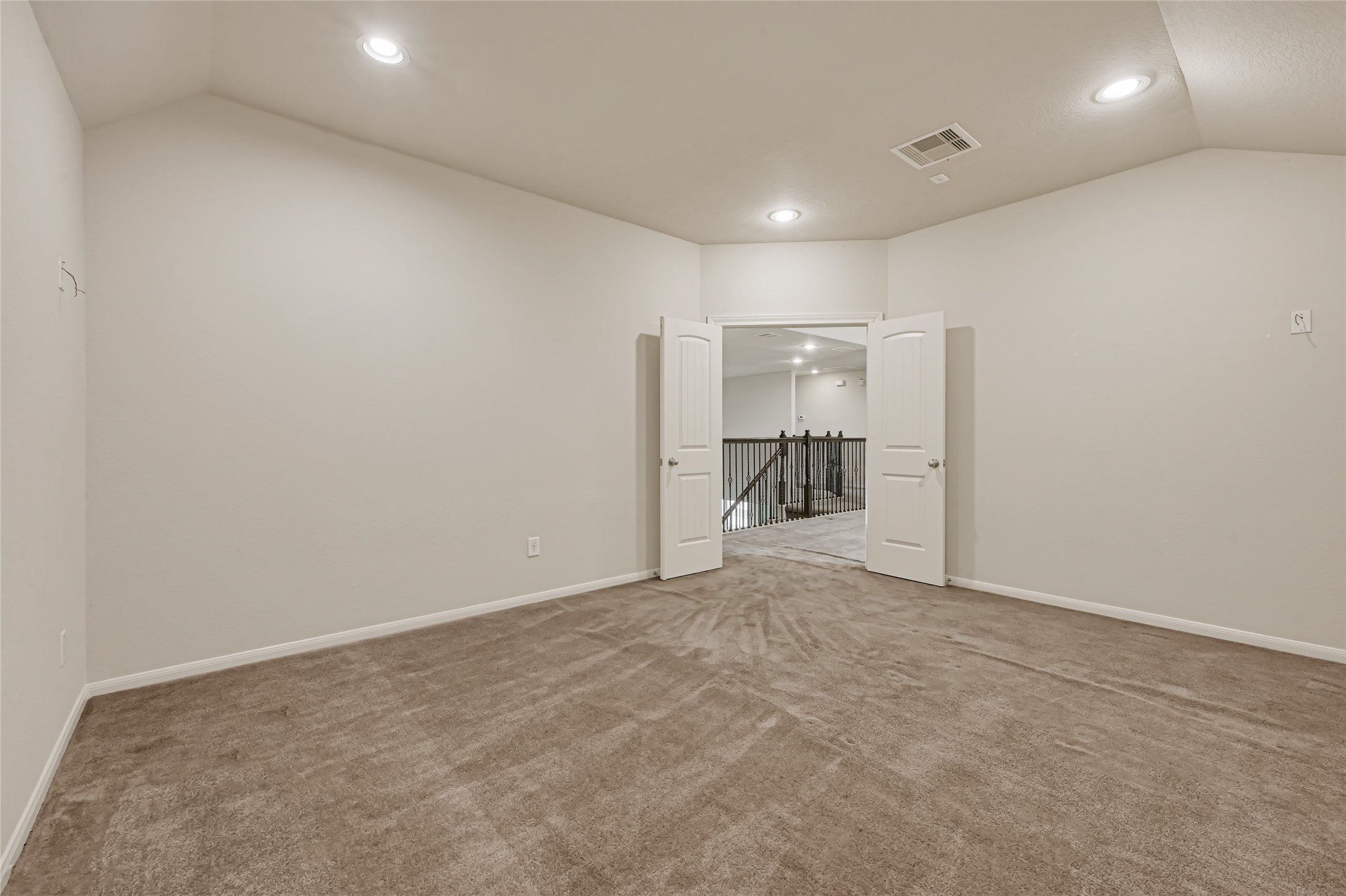 Bright primary bedroom with neutral carpet, recessed lighting, and a spacious layout.
