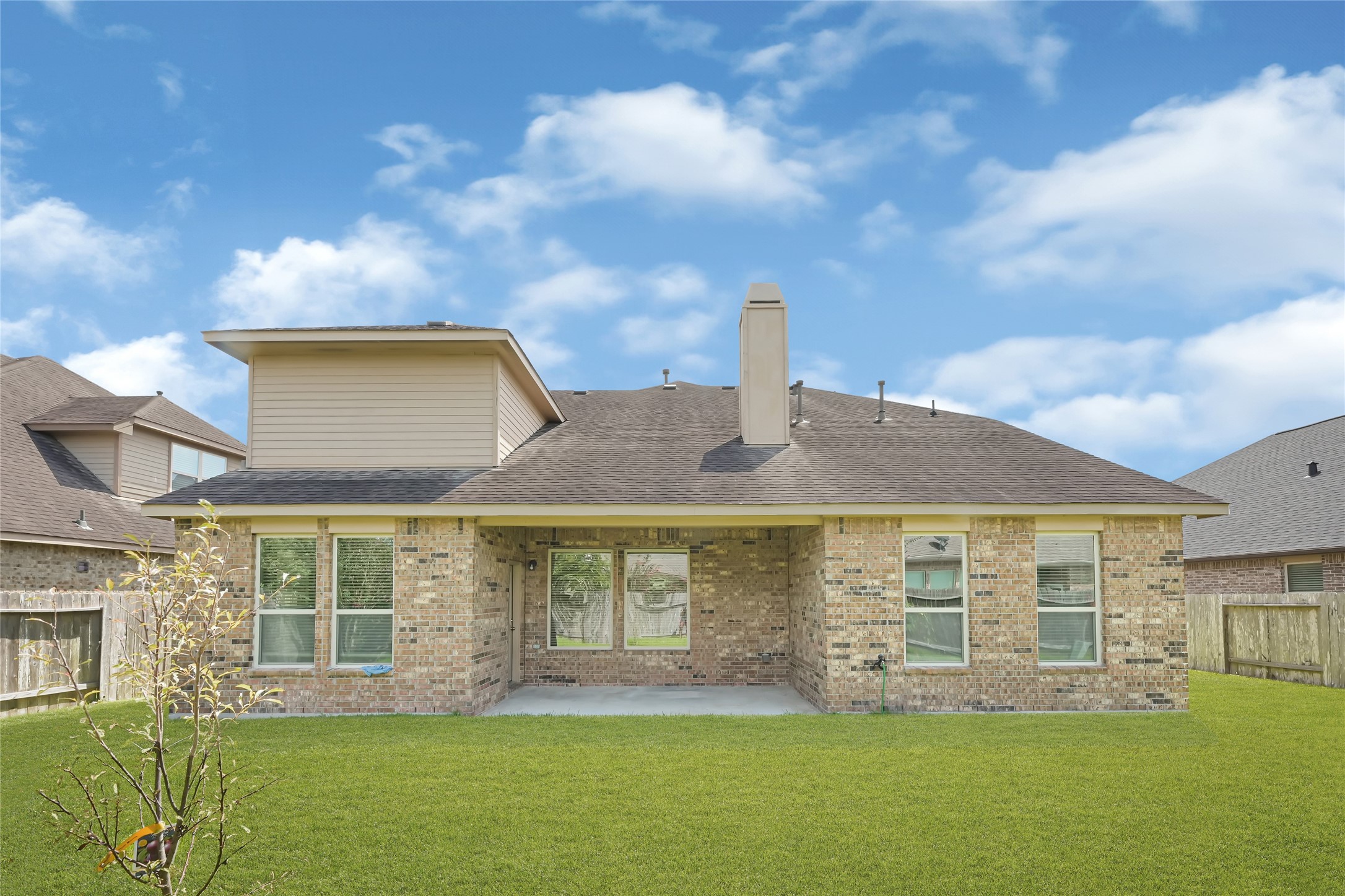 Spacious backyard with a full view of the homes brick exterior and multiple windows