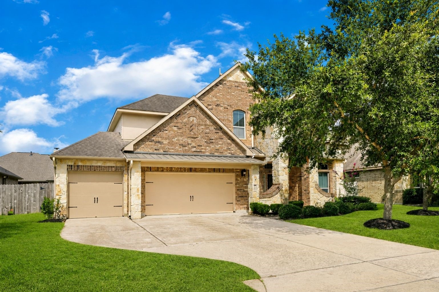 Attractive brick-and-stone home with a two-car garage, mature landscaping, and a spacious front lawn.