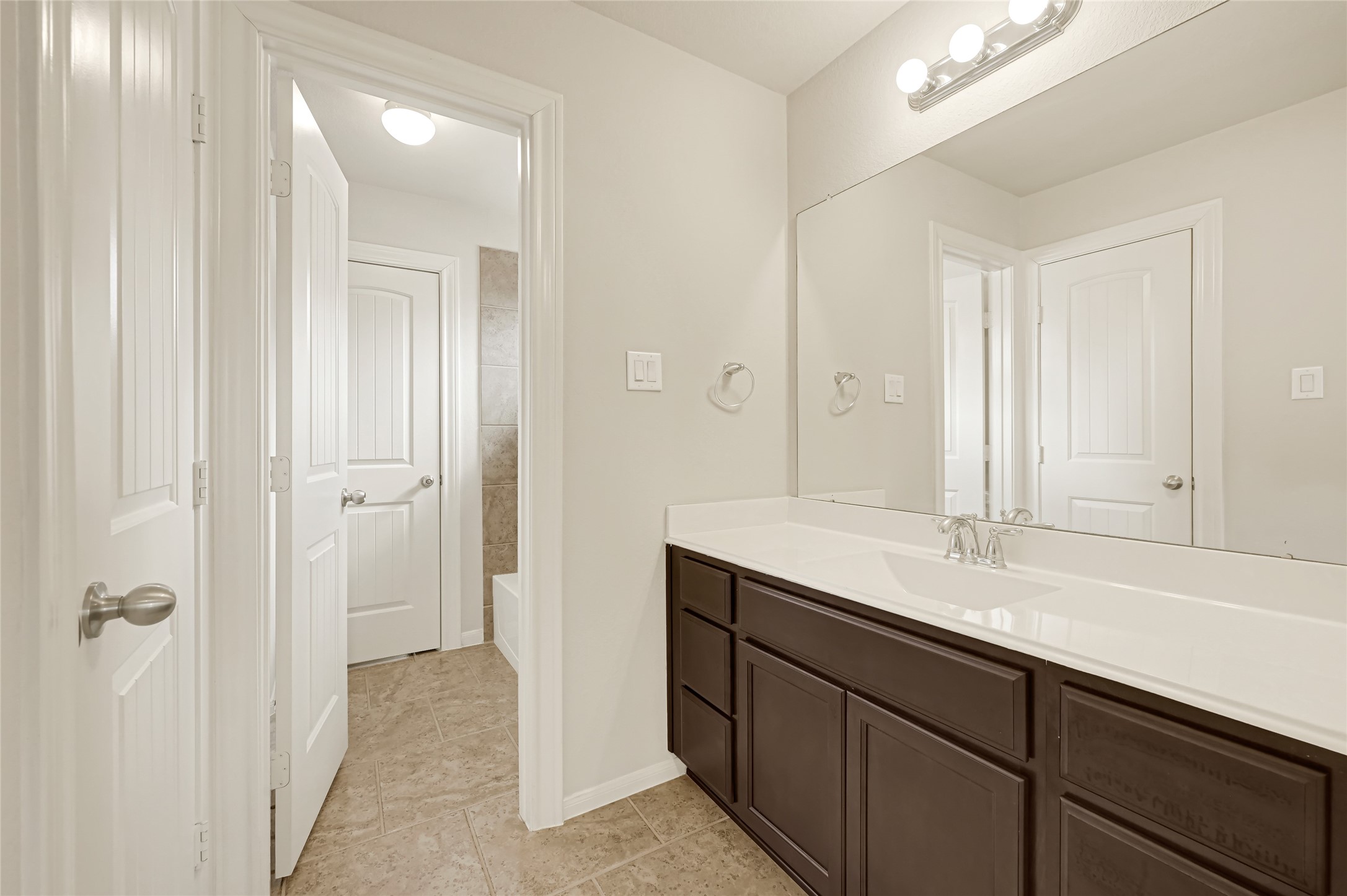 Well-appointed vanity with dark cabinetry, generous counter space, and access to the adjoining bath area.