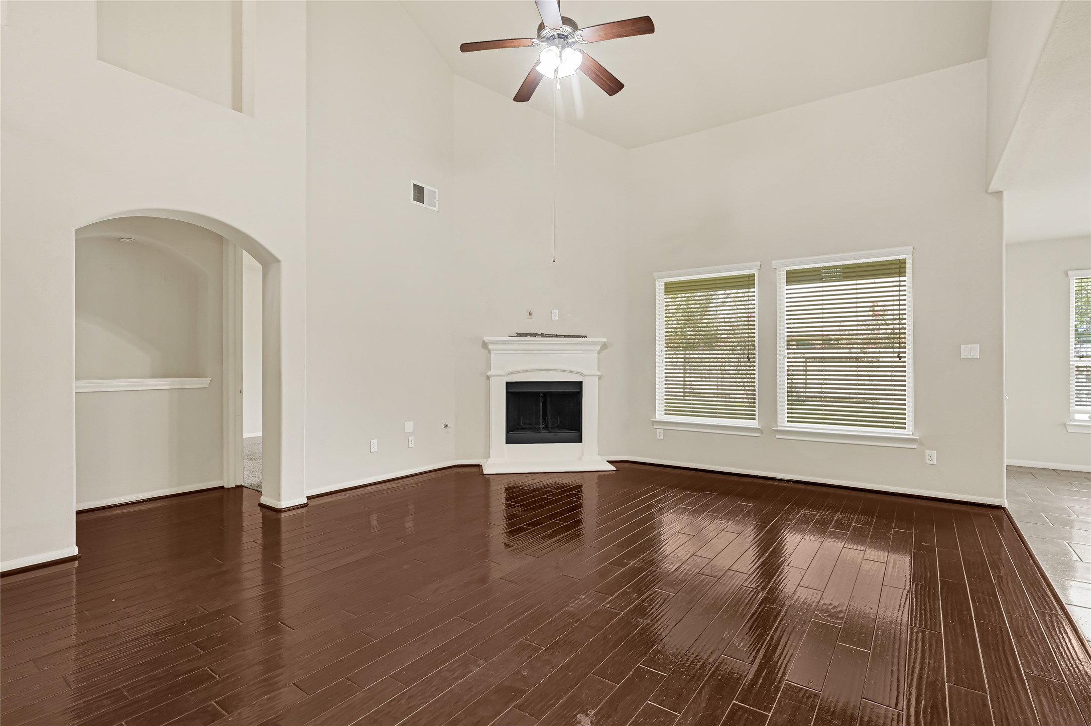 Formal dining room with hardwood flooring, crown molding, and an arched opening to the foyer.