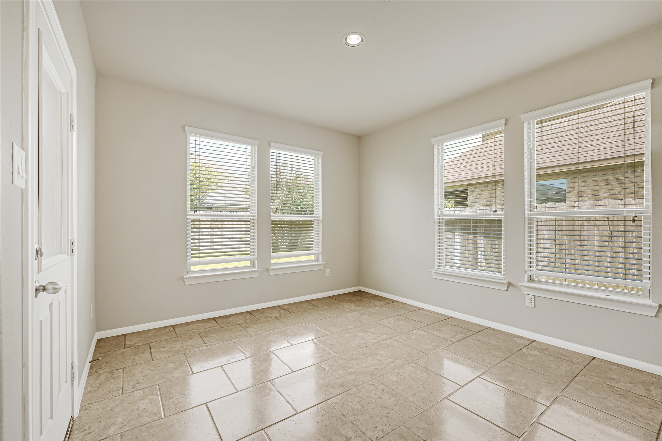 Bright enclosed flex room with tile flooring, multiple windows, and views of the backyard.