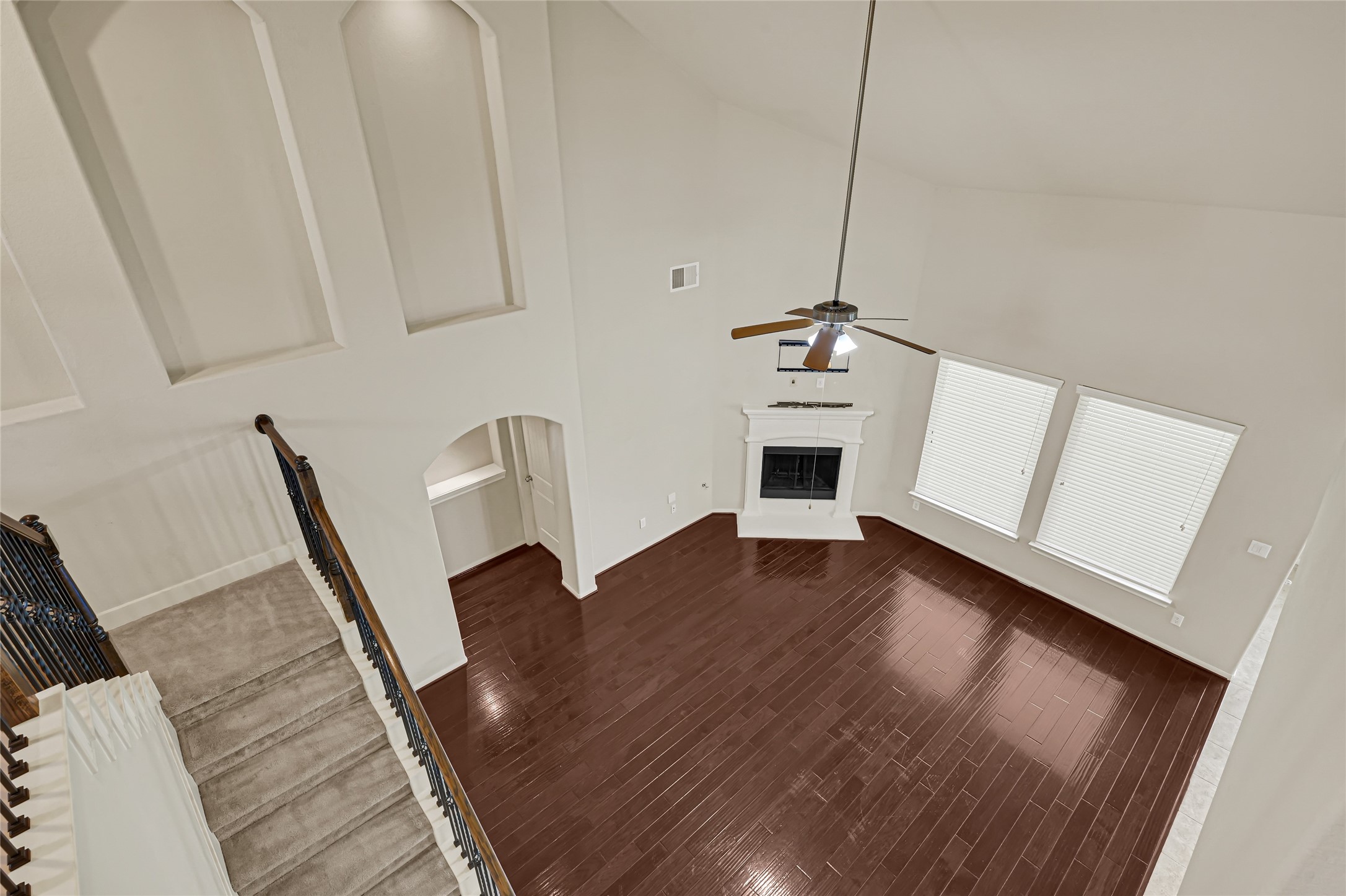 Elevated view of the hardwood foyer, entry doors, and open staircase.