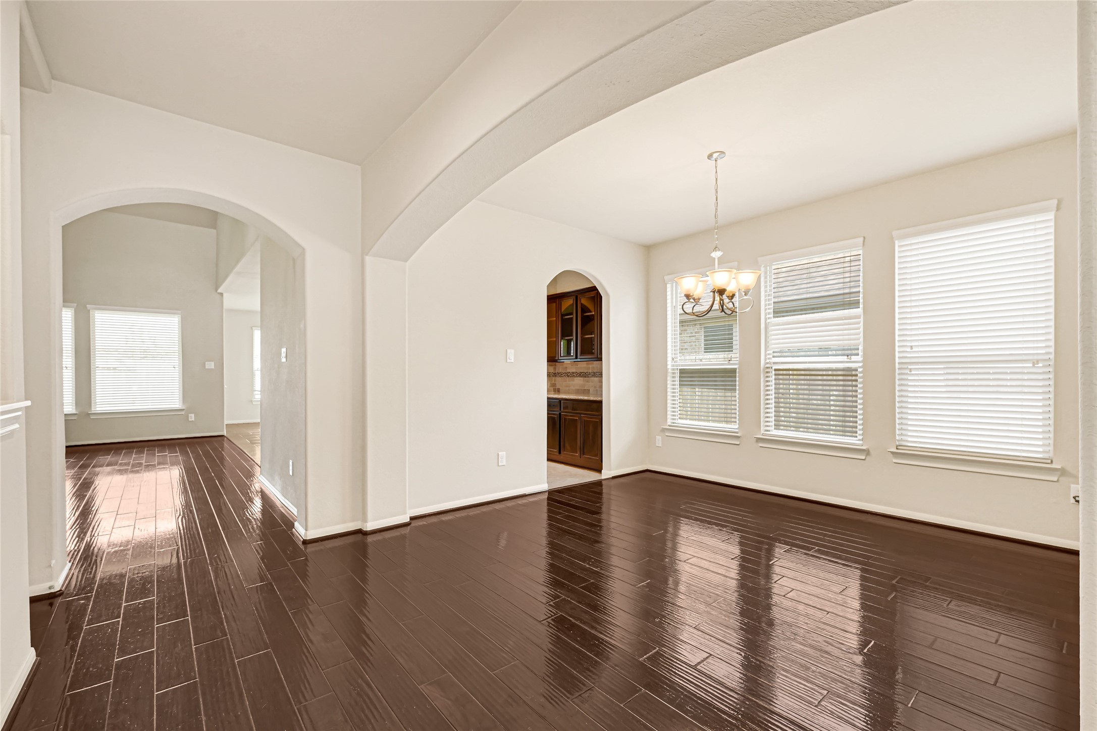 Formal dining space with hardwood flooring, arched openings, and abundant natural light.