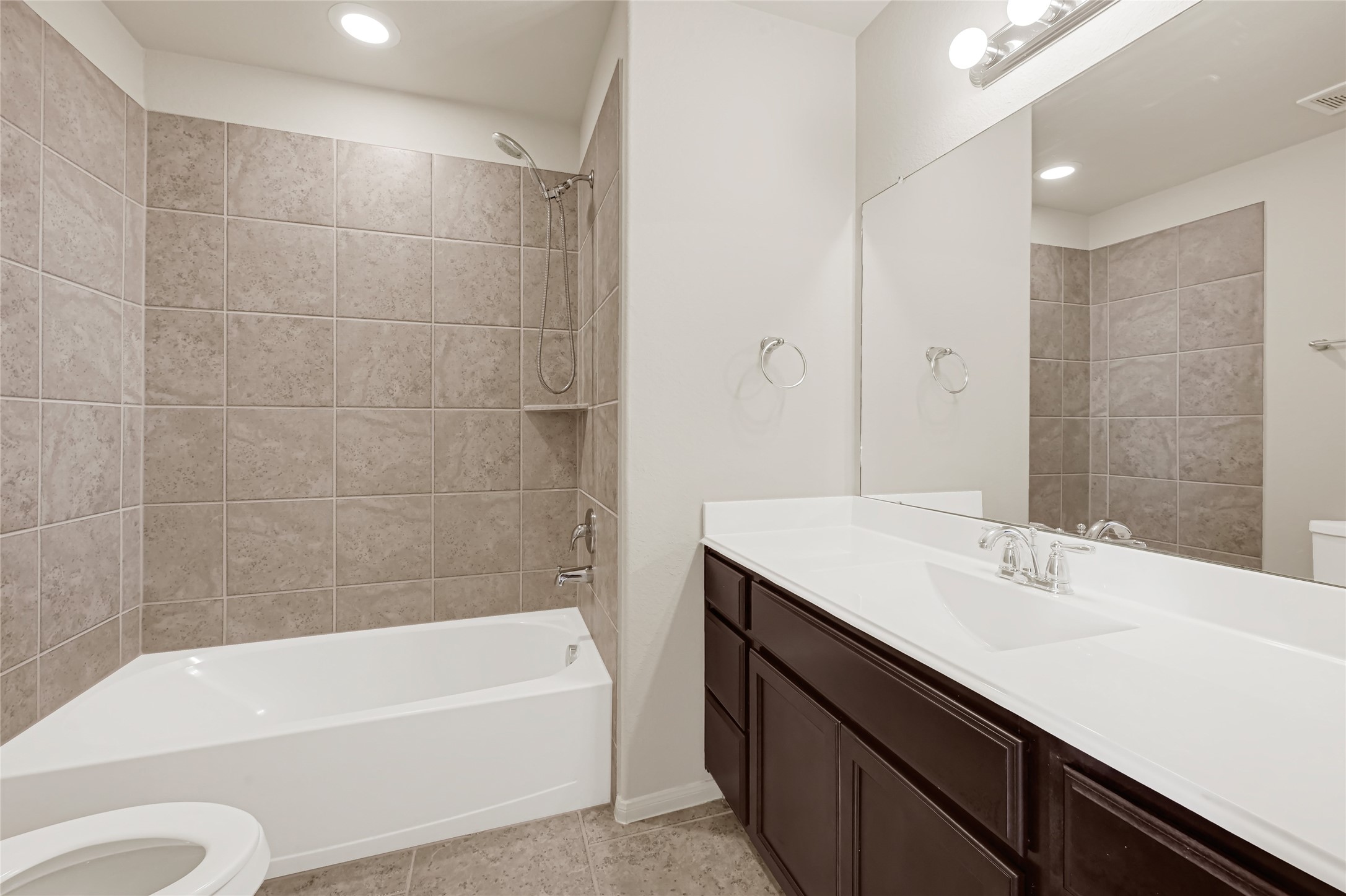 Full bathroom with a tub-and-shower combination, tiled surround, and an extended vanity.