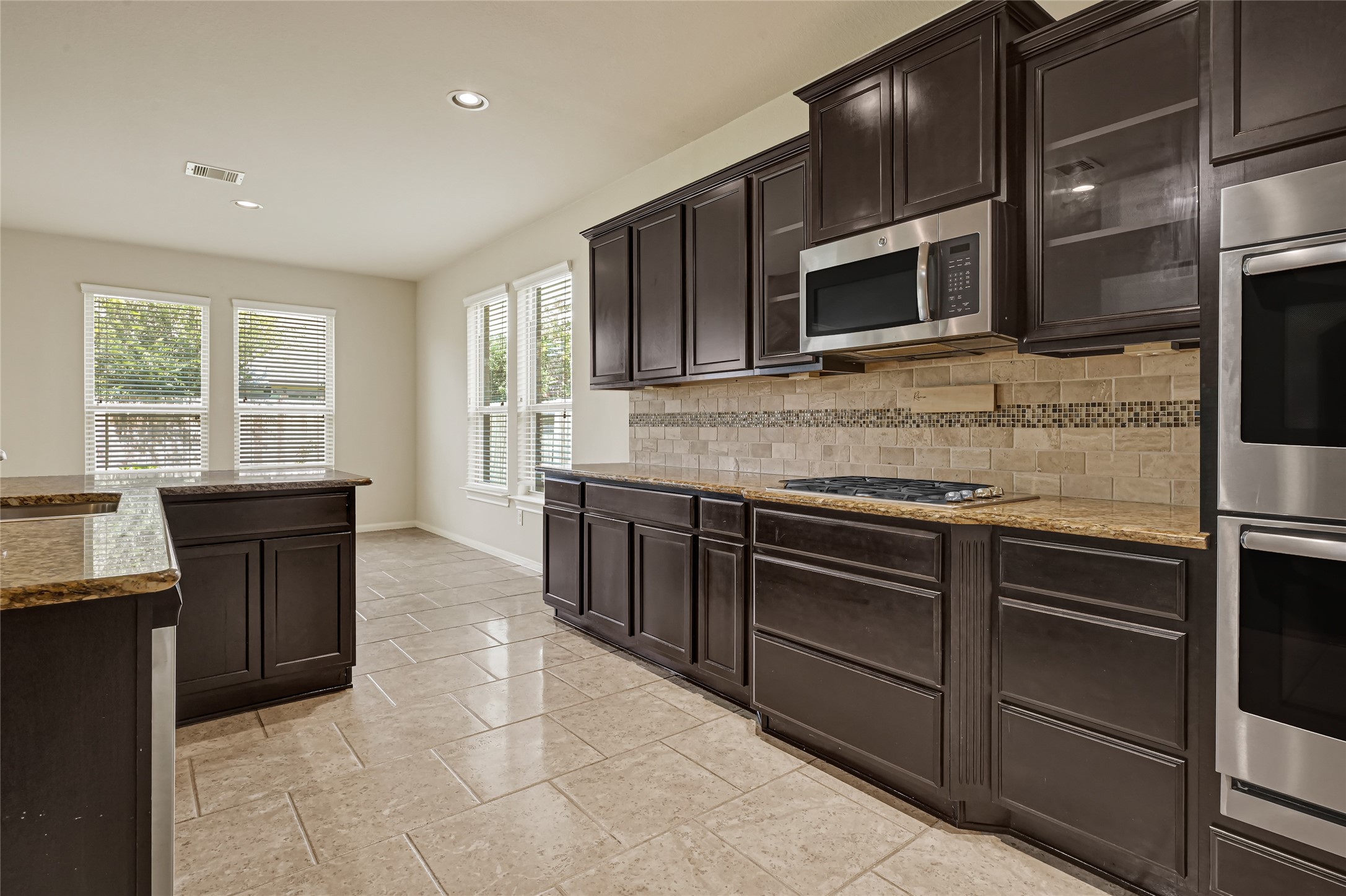 Spacious kitchen featuring dark cabinetry, granite countertops, tile flooring, and abundant storage.