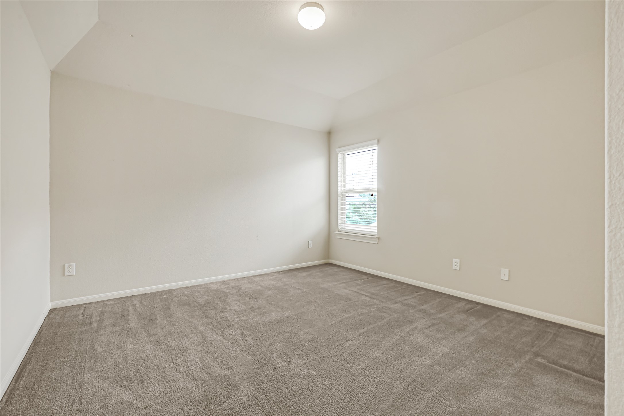 Spacious bedroom with neutral carpet, soft natural light, and a versatile layout