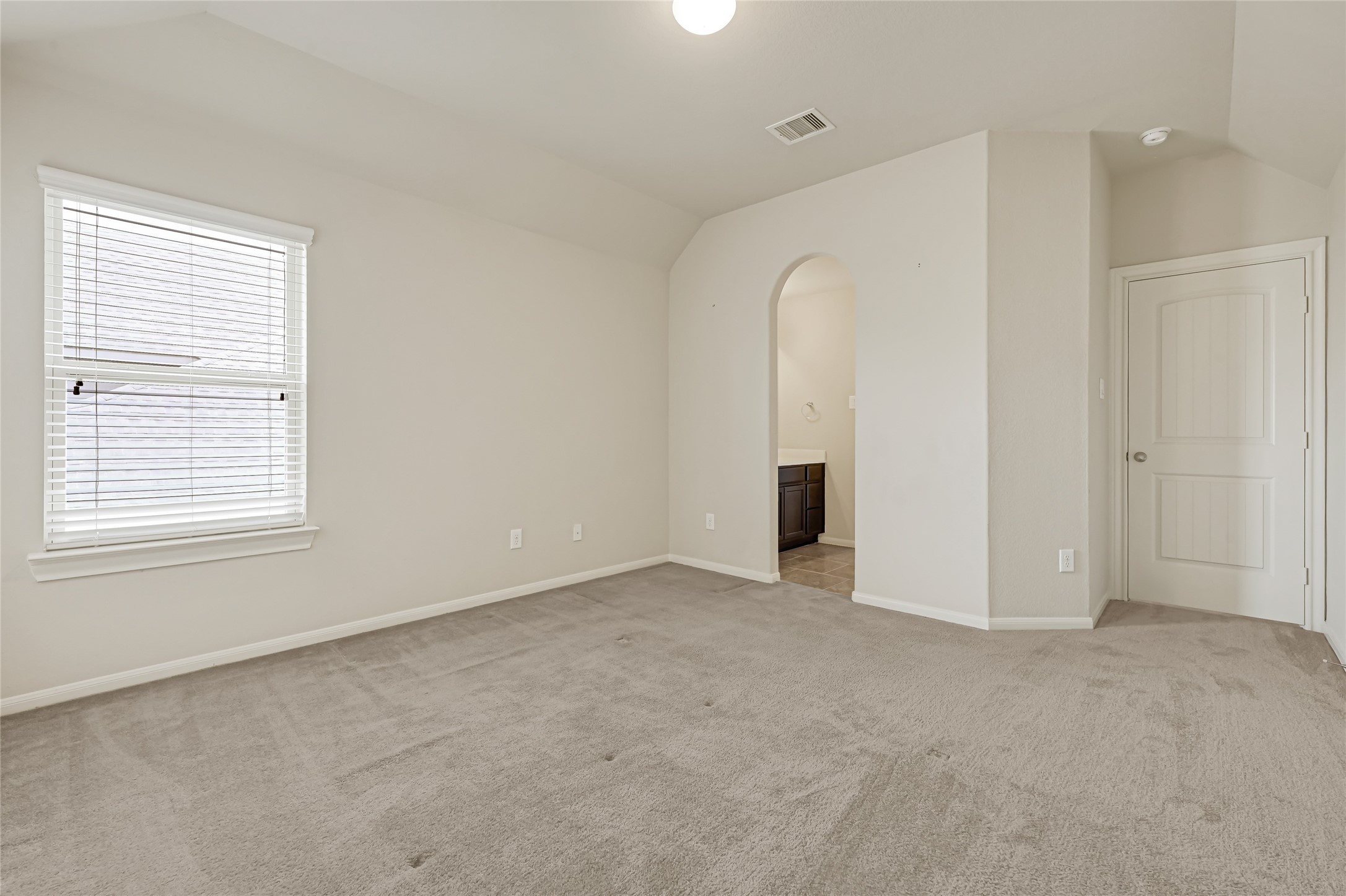 Bright bedroom with neutral carpet, natural light, and convenient access to the hallway.