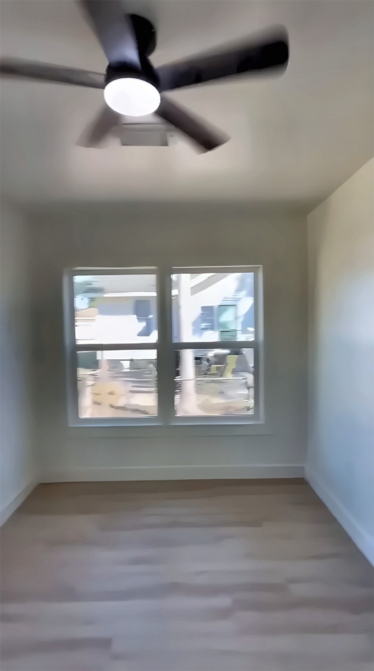 Room with two windows, wood-look flooring and ceiling fan