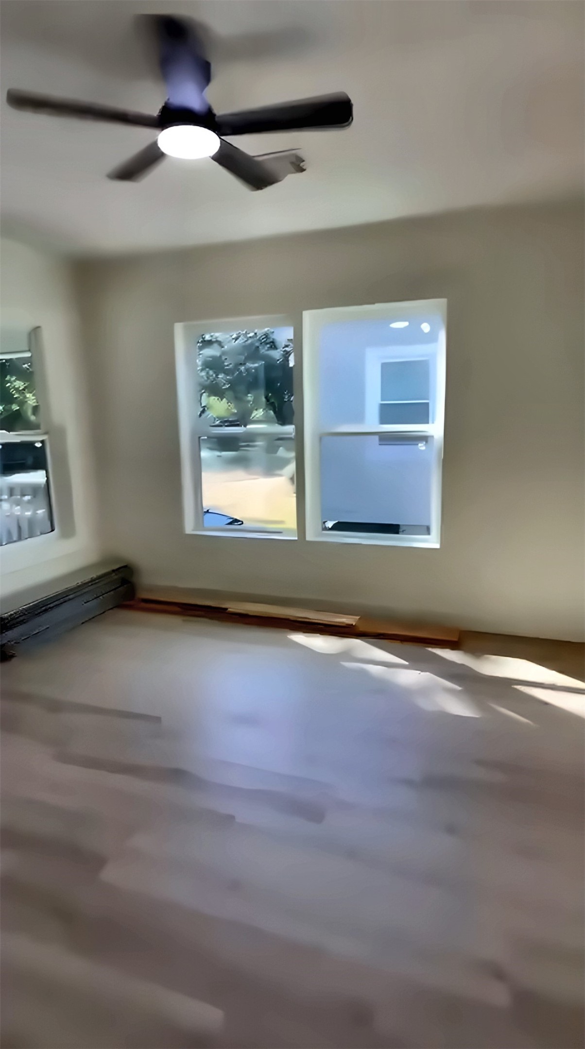 Room with windows, wood-look flooring and ceiling fan