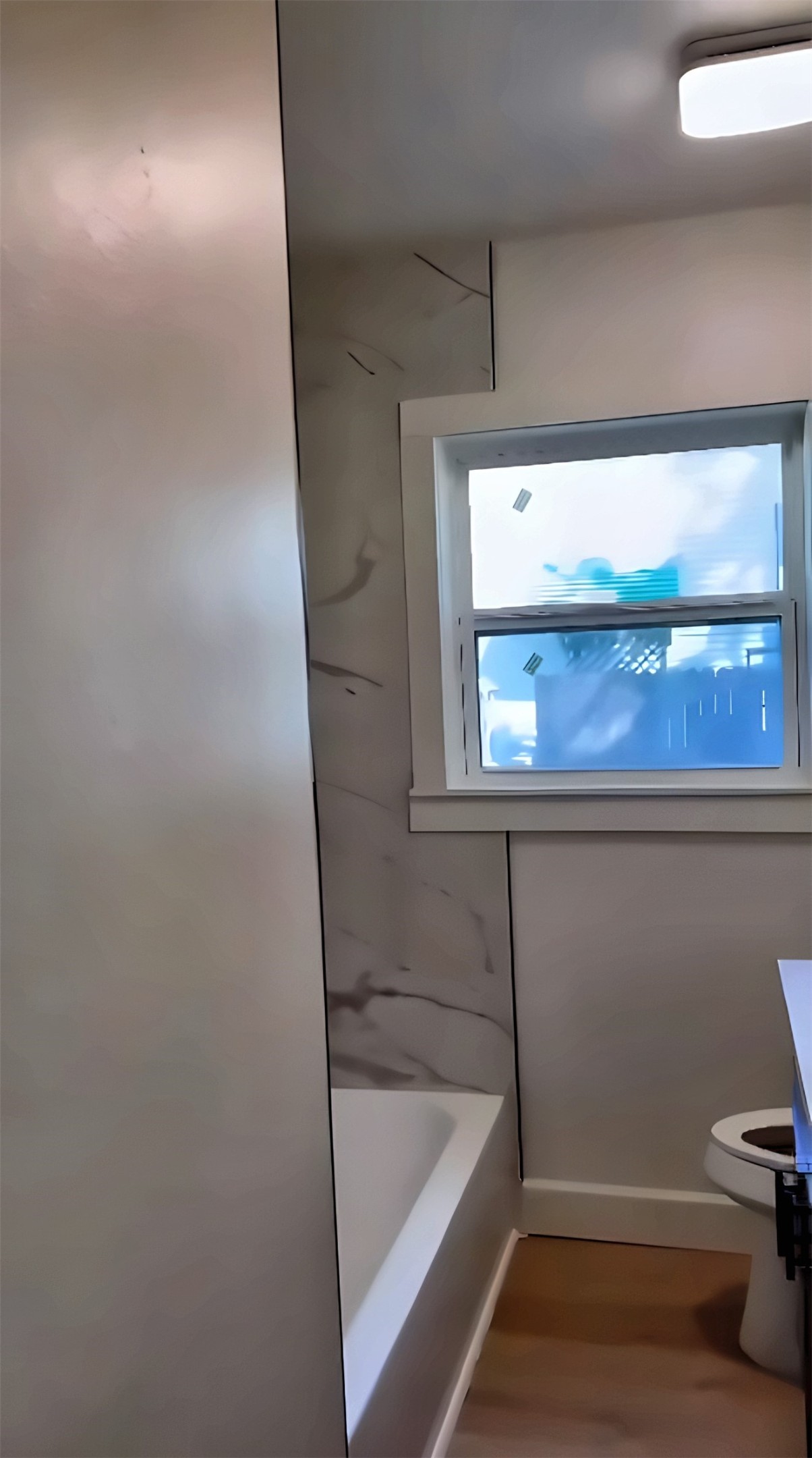 Bathroom with bathtub, tile wall and window