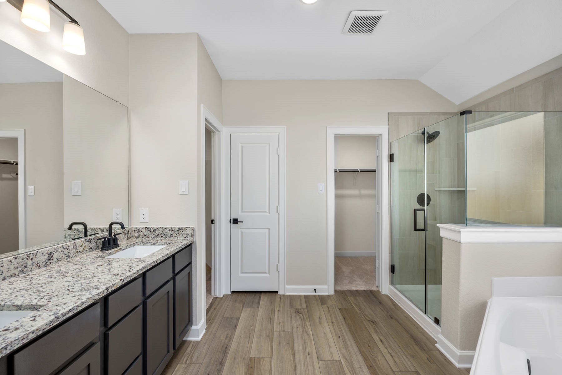 Indulge in luxury with this stunning primary bathroom featuring a spacious corner tub, a grand walk-in shower, and a sleek double sink vanity. Your personal oasis awaits!