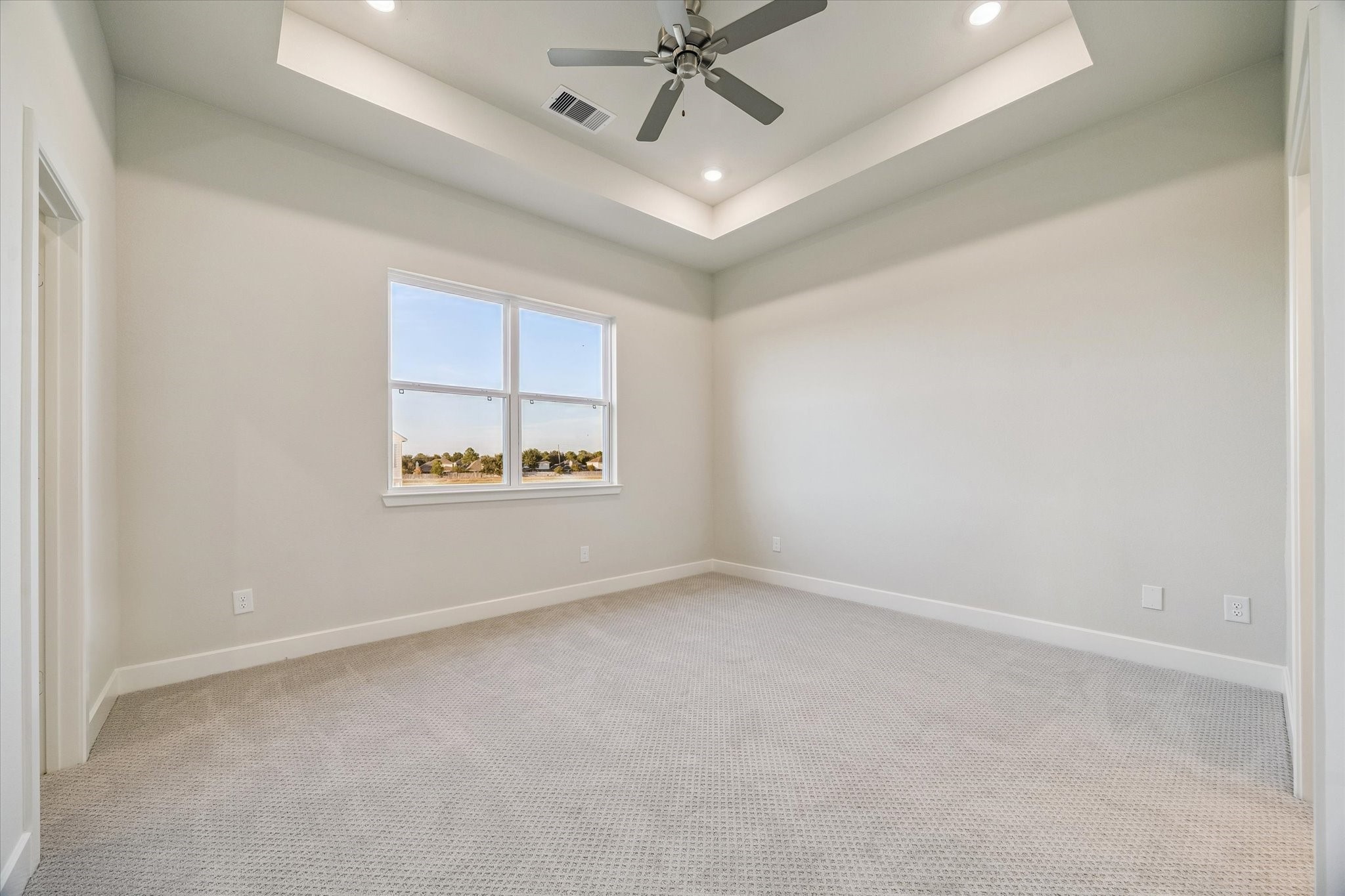 Large primary bedroom with trey ceiling