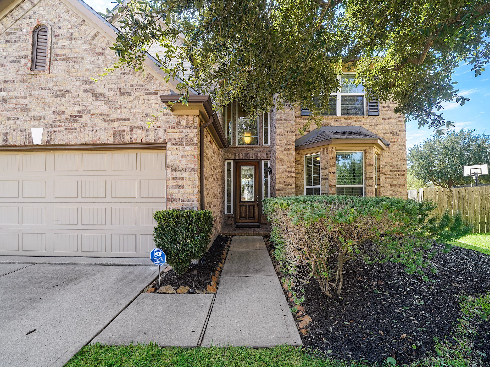 Mature landscaping welcomes you along the walkway to the front door, where a striking two-story arched entry creates a grand first impression. This elegant approach sets the tone for the warmth and charm waiting inside.