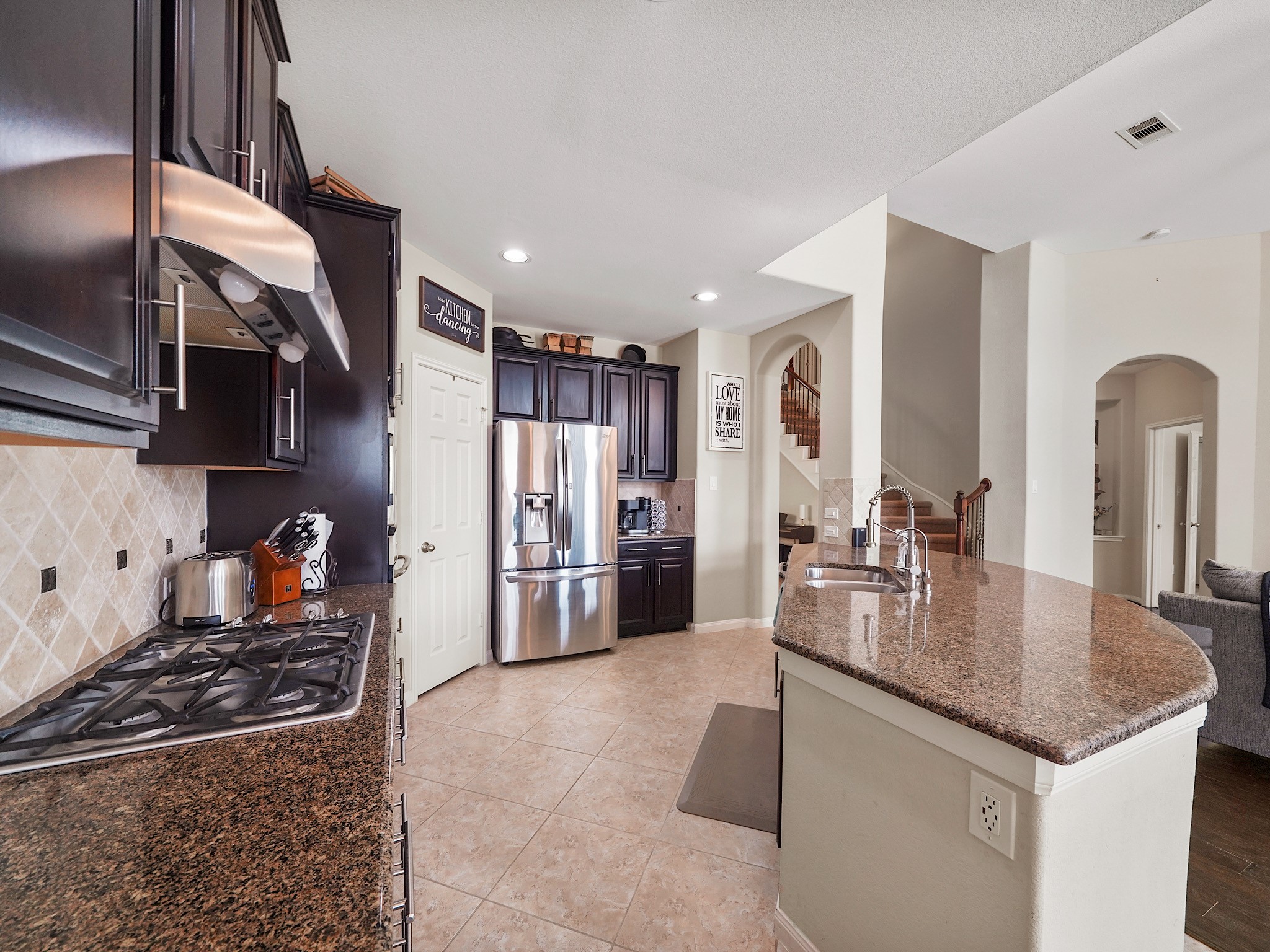 Rich wood cabinetry offers an abundance of storage, while the large pantry provides even more room for everyday essentials and entertaining favorites.