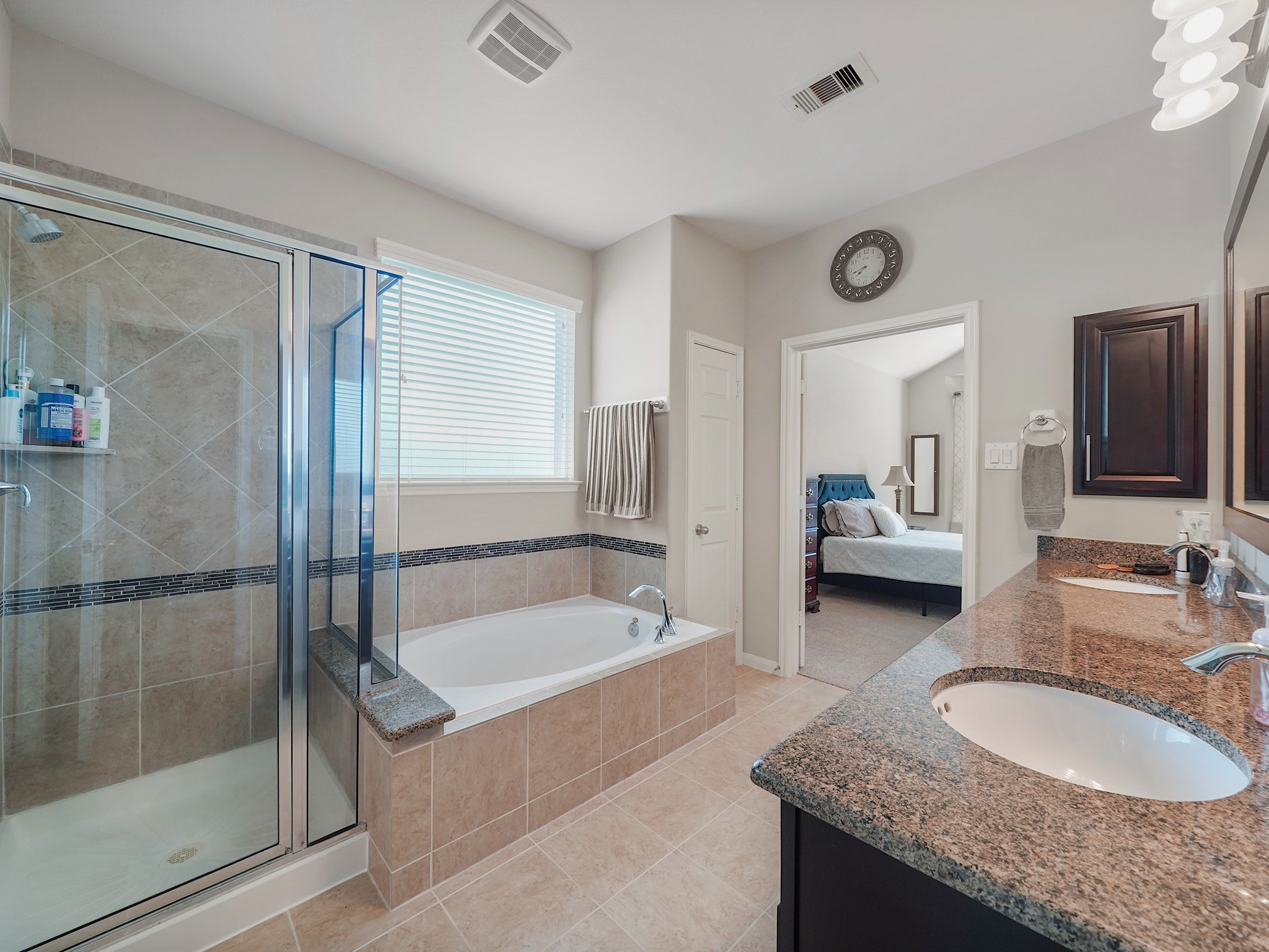 The spacious primary bathroom offers a serene extension of the retreat, complete with a soaking tub, separate glass-enclosed shower, and an extended dual-sink vanity with granite countertops. Its a space designed to bring comfort and ease to your daily routine.