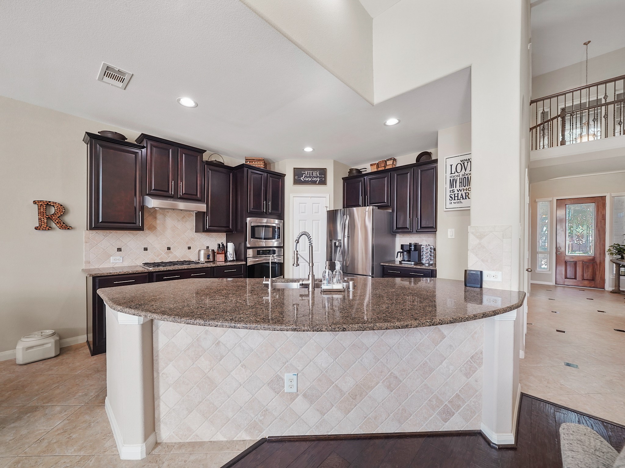 Spacious kitchen with dark wood cabinetry, granite countertops, and stainless steel appliances, featuring a large island perfect for entertaining.