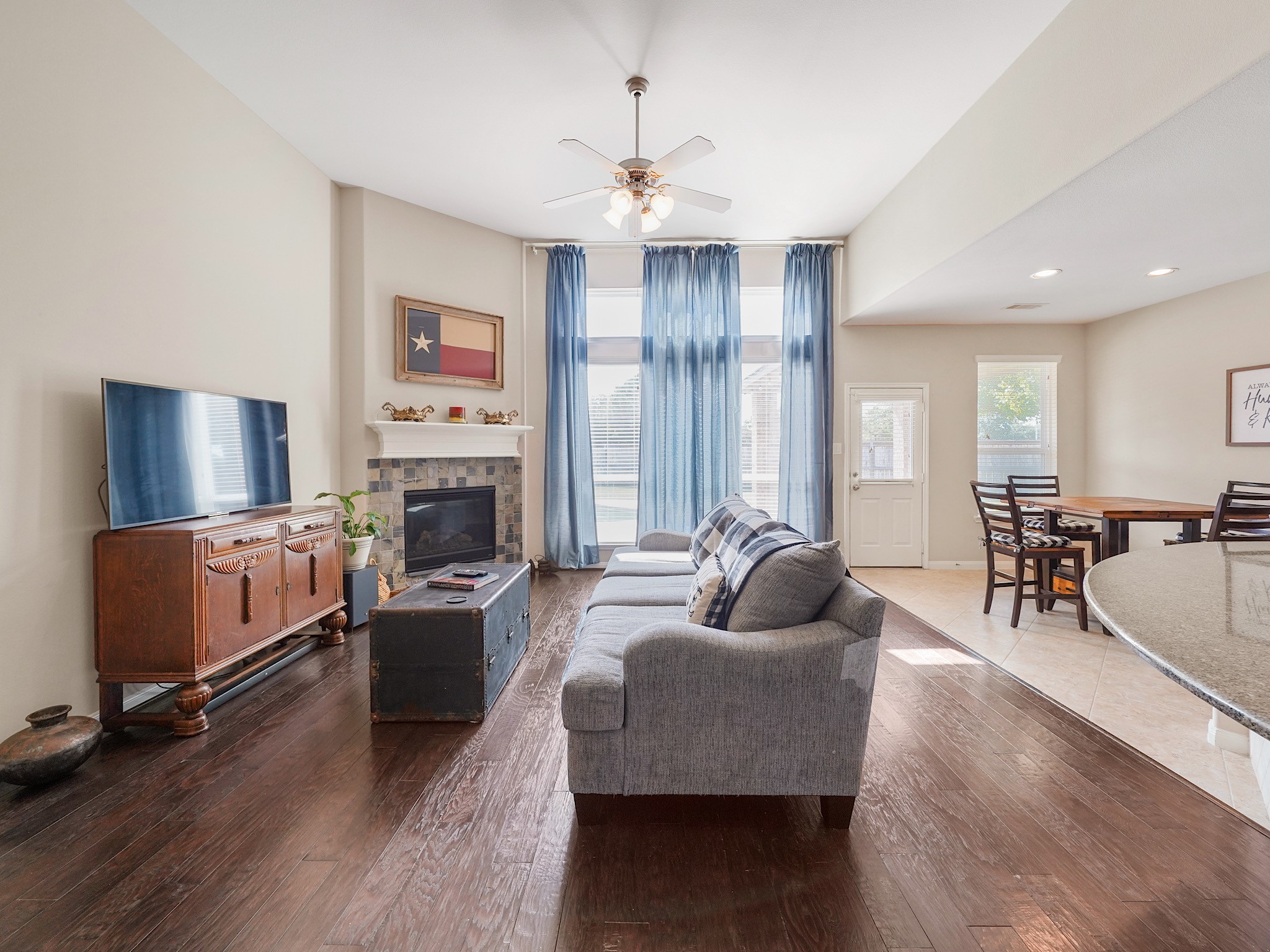 Large windows fill the living area with natural light, complementing the high ceilings and creating a beautiful sense of openness. Imagine enjoying a quiet morning here or gathering with loved ones at the end of the day in this warm and inviting space.
