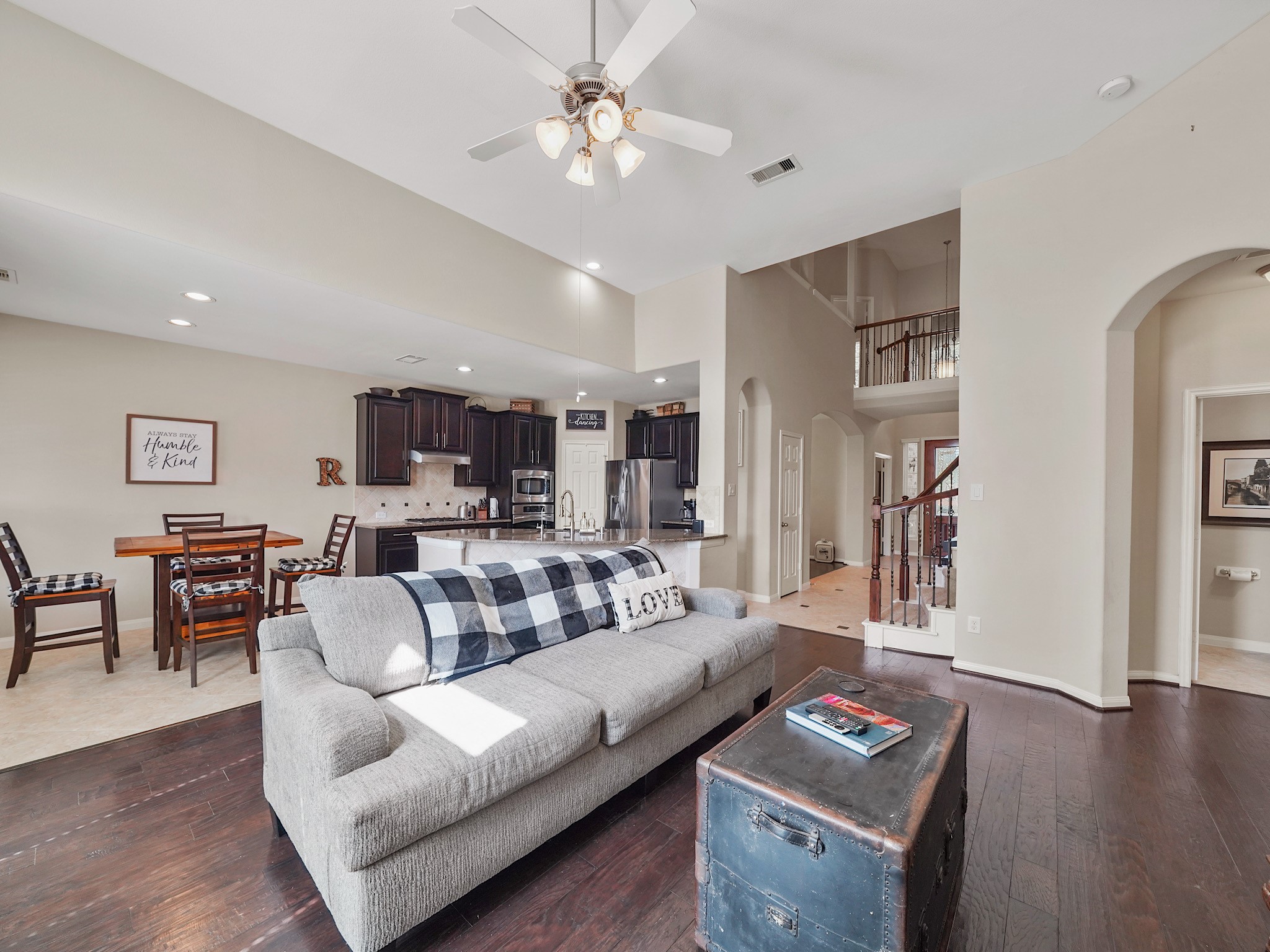 High ceilings and abundant natural light create an open, welcoming atmosphere in the living area, which flows into the kitchen. Dark cabinetry and a central island add a touch of sophistication, while the open layout makes it easy to stay connected whether preparing a meal or relaxing together.