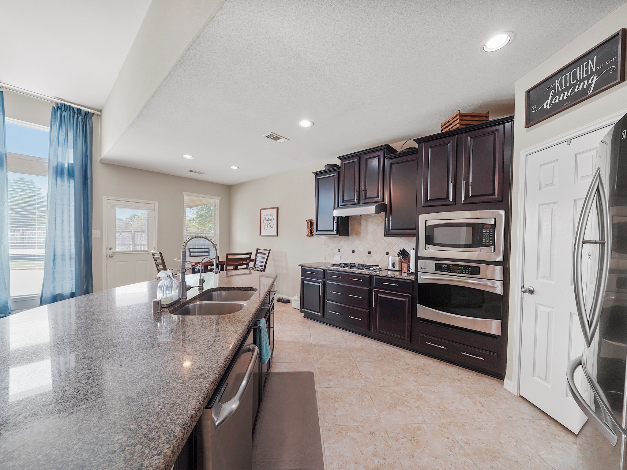 The central island offers space to prepare meals, serve appetizers, and gather for conversation. Granite countertops add a polished touch, creating a kitchen that feels equally suited to everyday routines and special occasions.