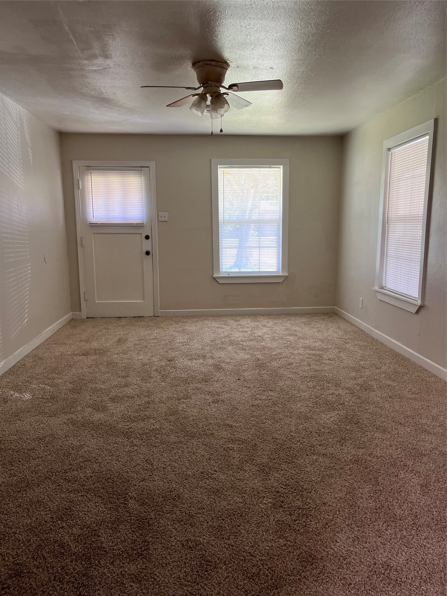 Looking towards the front door entrance.  Ceiling fan and lots of light from windows.