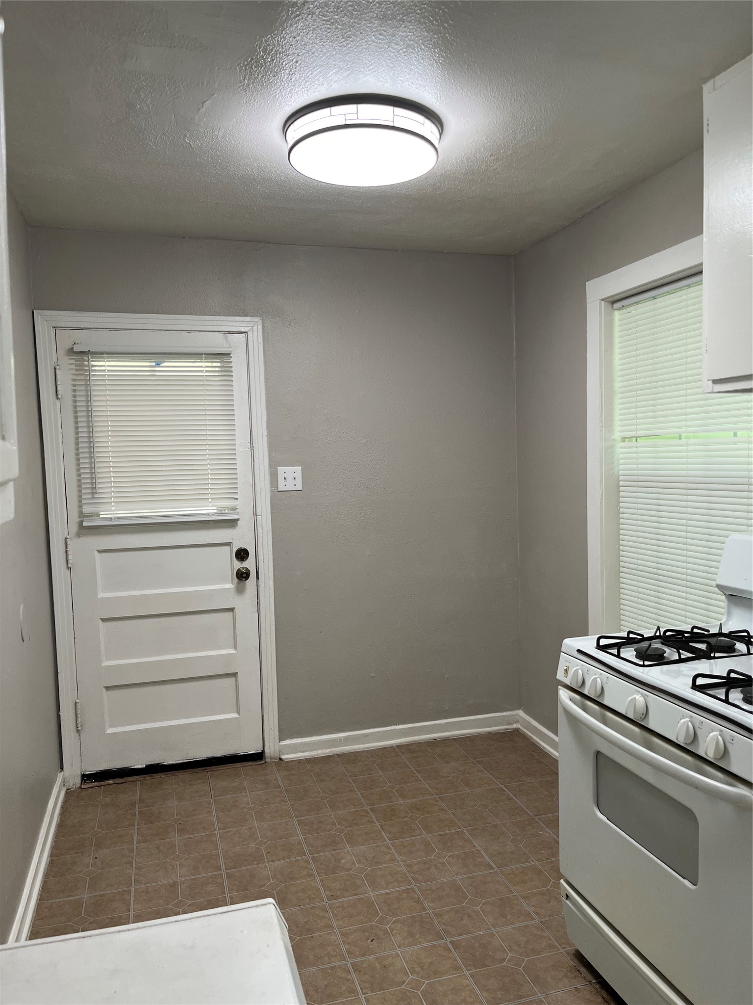 Breakfast area in the kitchen, door leads to old garage and storage area. Large window overlooks the large backyard