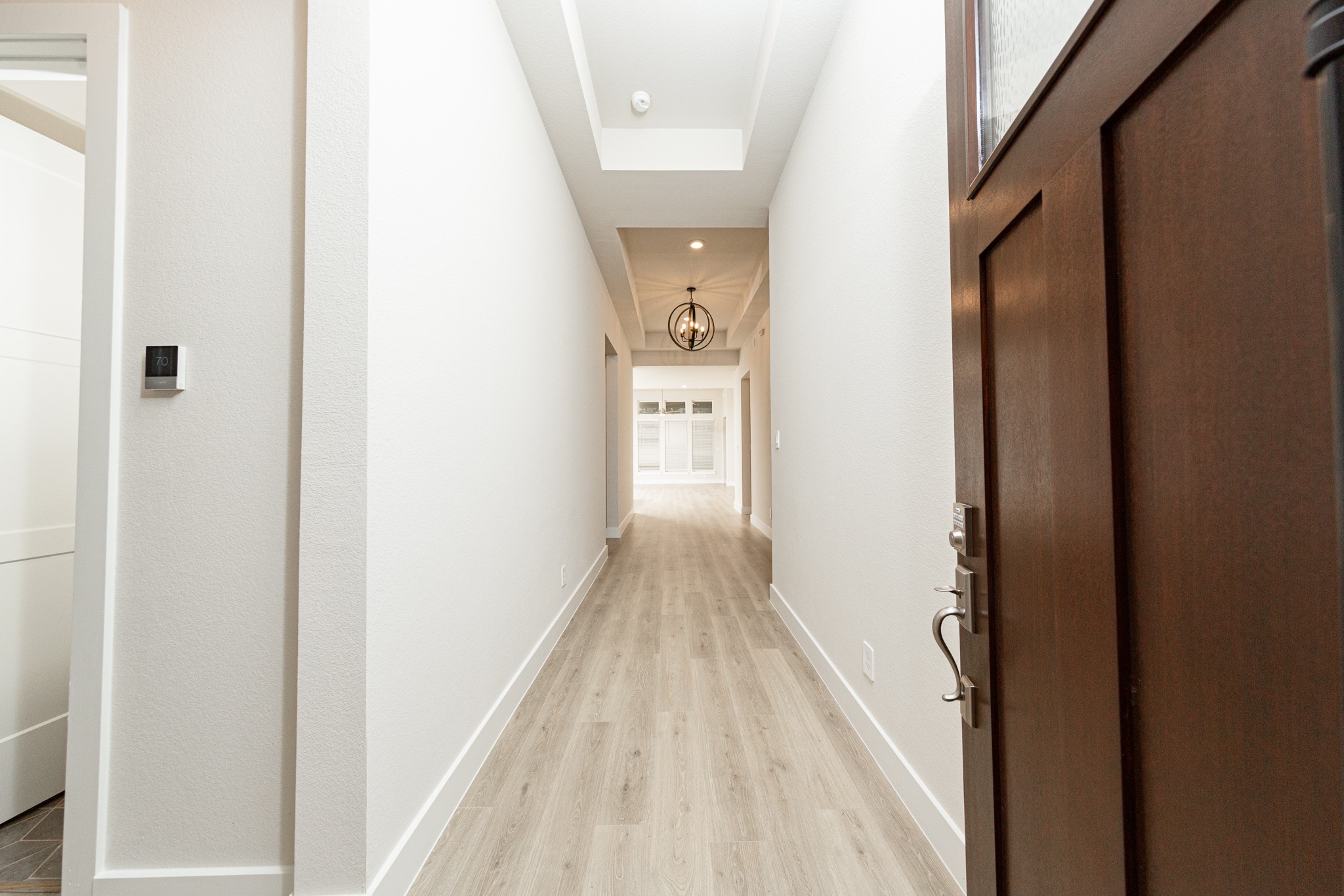 An inviting entrance opens up to an open-concept layout, seamlessly connecting the entry to the living areas with durable wood look tile flooring and striking architectural details.