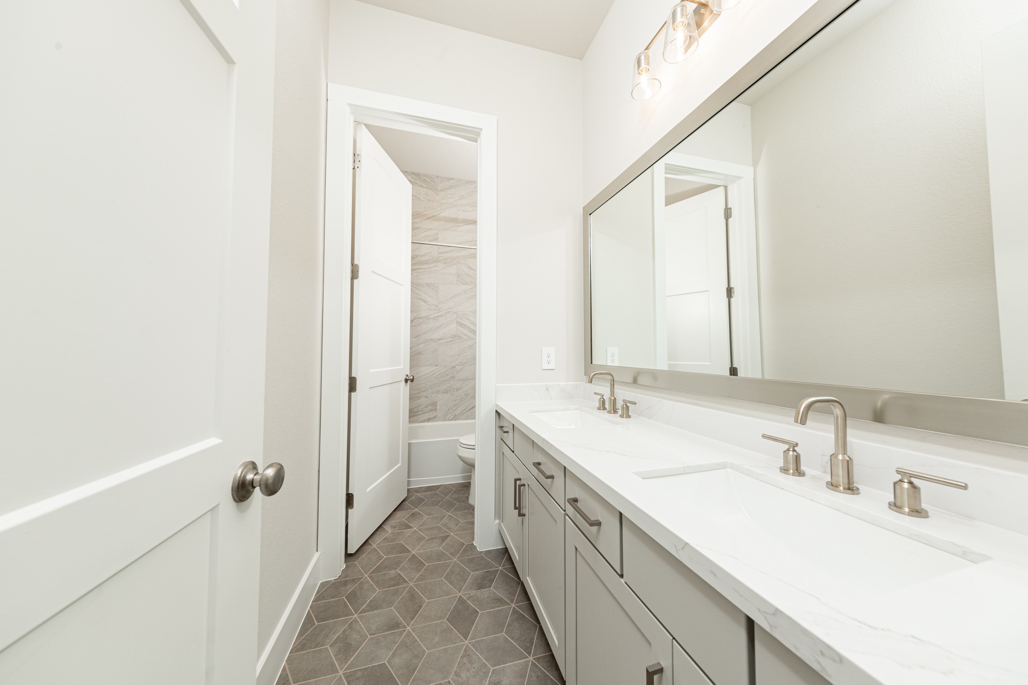 The secondary bathroom features a dual vanity, framed mirror, tub/shower combination with gorgeous tile surround, and modern brushed nickel finishes.